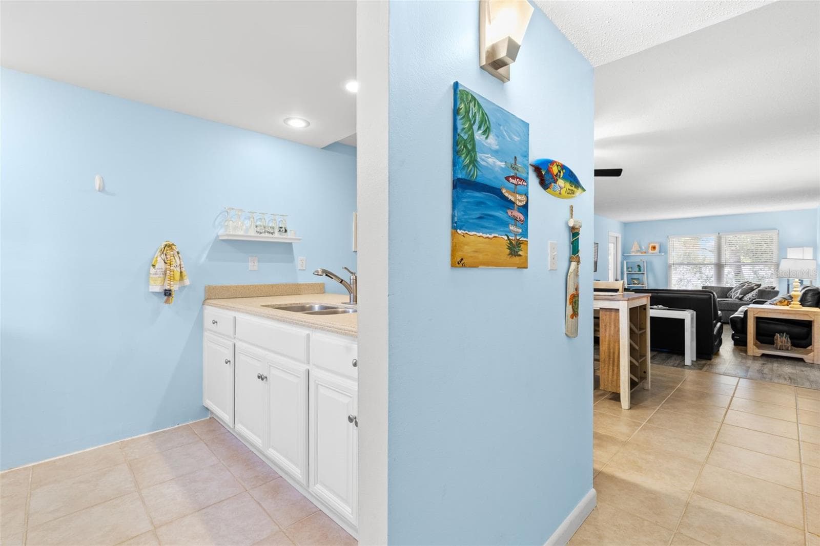 Just inside the entry, the kitchen opens toward the dining and living areas, creating a natural connection through the main living space, with tile flooring, light cabinetry and a double-basin sink. - 12760 INDIAN ROCKS RD #107, LARGO