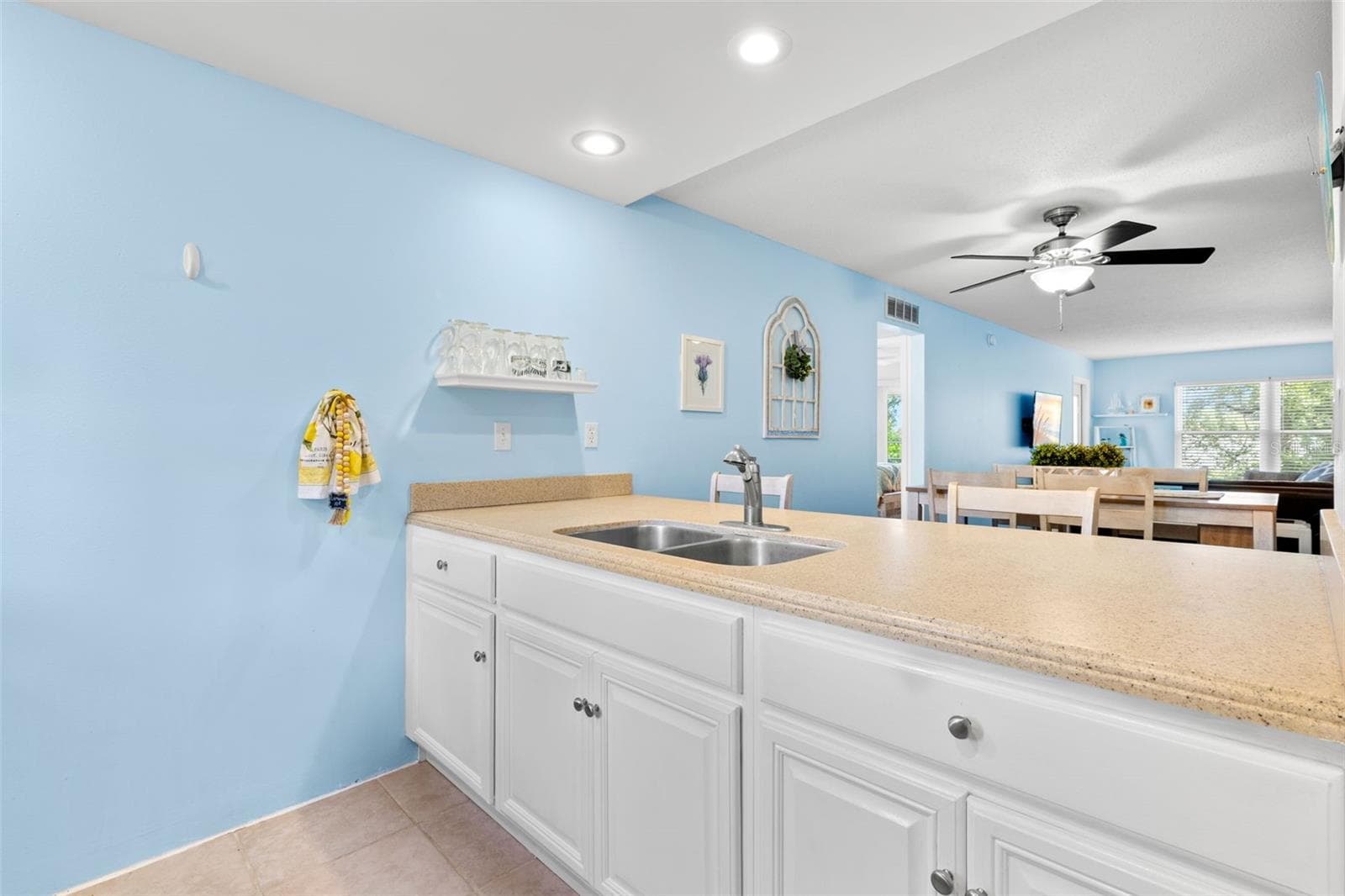 A long Corian breakfast bar extends the kitchen toward the dining and living areas, pairing generous counter space with a double-basin sink while keeping the room visually connected to the main living space. - 12760 INDIAN ROCKS RD #107, LARGO