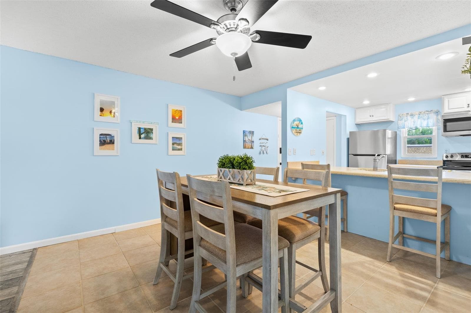 The dining area sits just beyond the kitchen, with tile flooring, a ceiling fan overhead and enough room for a full dining set, while the breakfast bar adds extra seating along the kitchen edge. - 12760 INDIAN ROCKS RD #107, LARGO