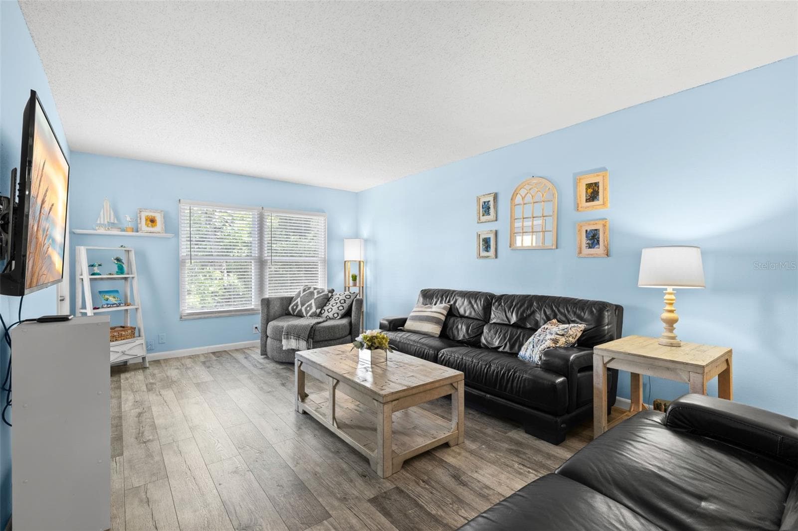 The 20-foot living room offers plenty of space for a full seating arrangement, with luxury vinyl flooring and a wide bank of windows drawing natural light across the room. - 12760 INDIAN ROCKS RD #107, LARGO