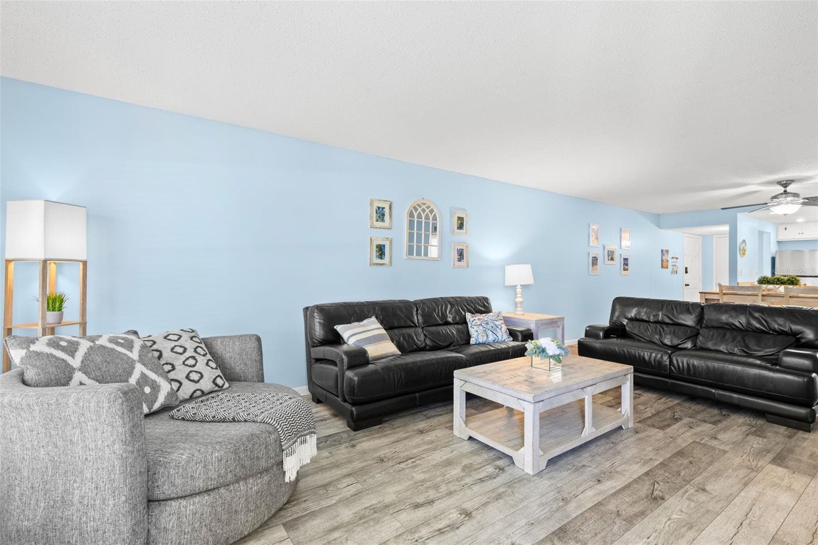 Looking back toward the dining area and kitchen, the living room’s generous proportions become even clearer, with luxury vinyl flooring, multiple seating areas and an open sightline that carries through the main living space. - 12760 INDIAN ROCKS RD #107, LARGO