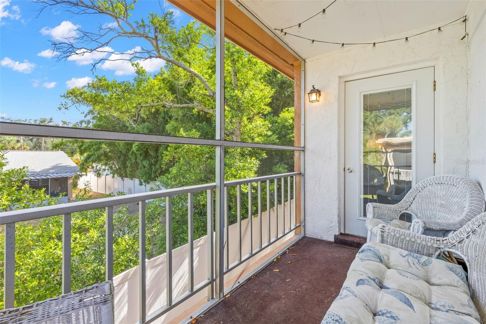 Positioned between the living room and primary bedroom, the screened balcony creates a comfortable outdoor extension of both spaces, with room for seating and a leafy view framed by mature trees. - 12760 INDIAN ROCKS RD #107, LARGO