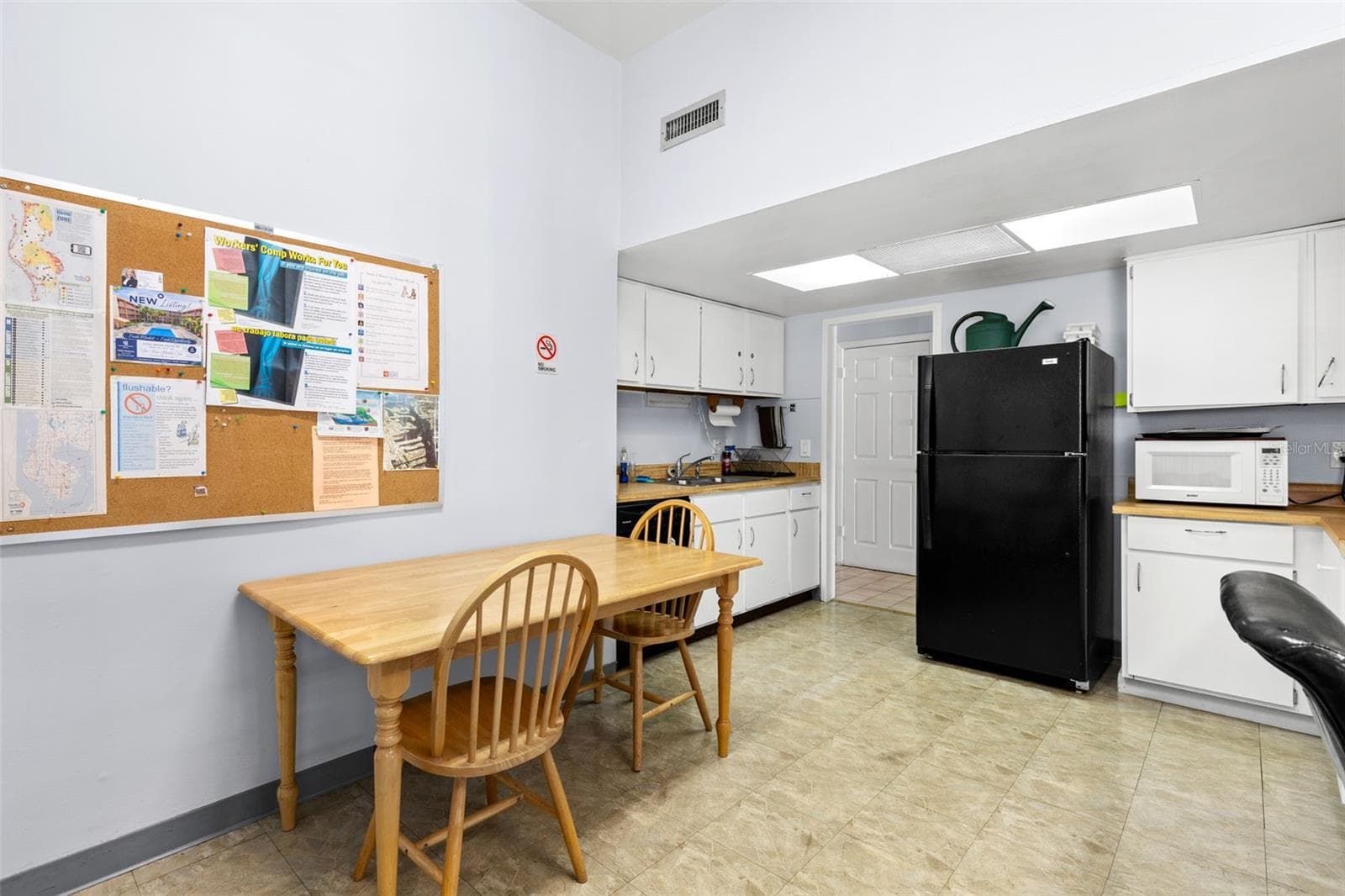 The clubhouse includes a community kitchen with full-size refrigerator, microwave, sink, cabinetry and table seating, providing space for gatherings and shared activities. - 12760 INDIAN ROCKS RD #107, LARGO
