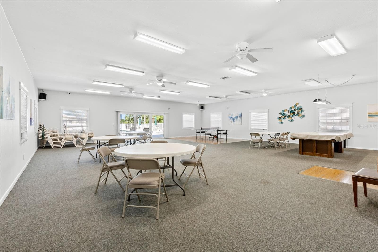The clubhouse provides plenty of room to gather, with multiple tables for cards or games, billiards and ping-pong, plus doors opening toward the pool area. - 12760 INDIAN ROCKS RD #107, LARGO