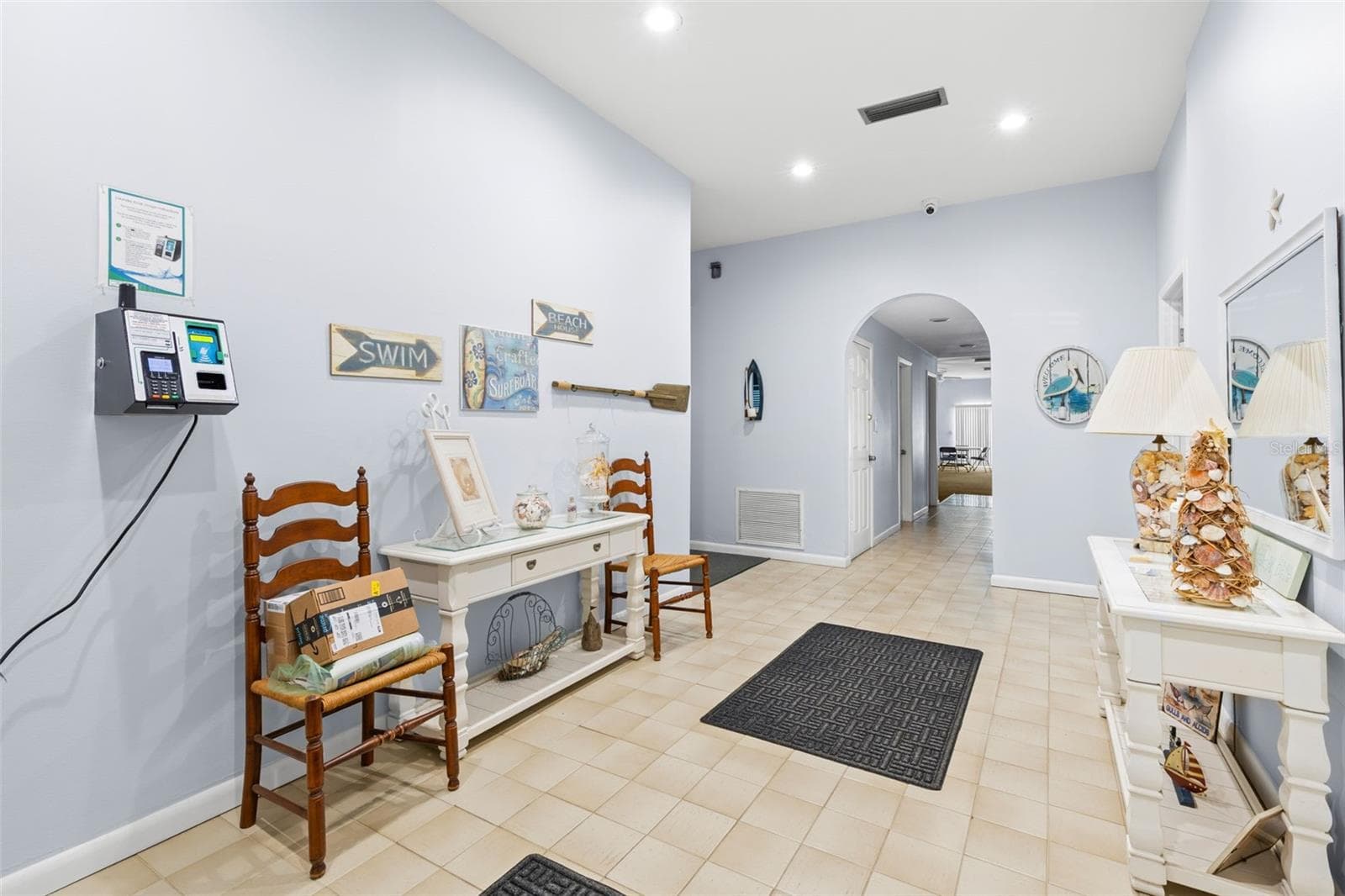 The clubhouse entry hall is finished with tile flooring and recessed lighting, with a welcoming coastal theme and easy access to the community’s gathering and recreation spaces beyond. - 12760 INDIAN ROCKS RD #107, LARGO