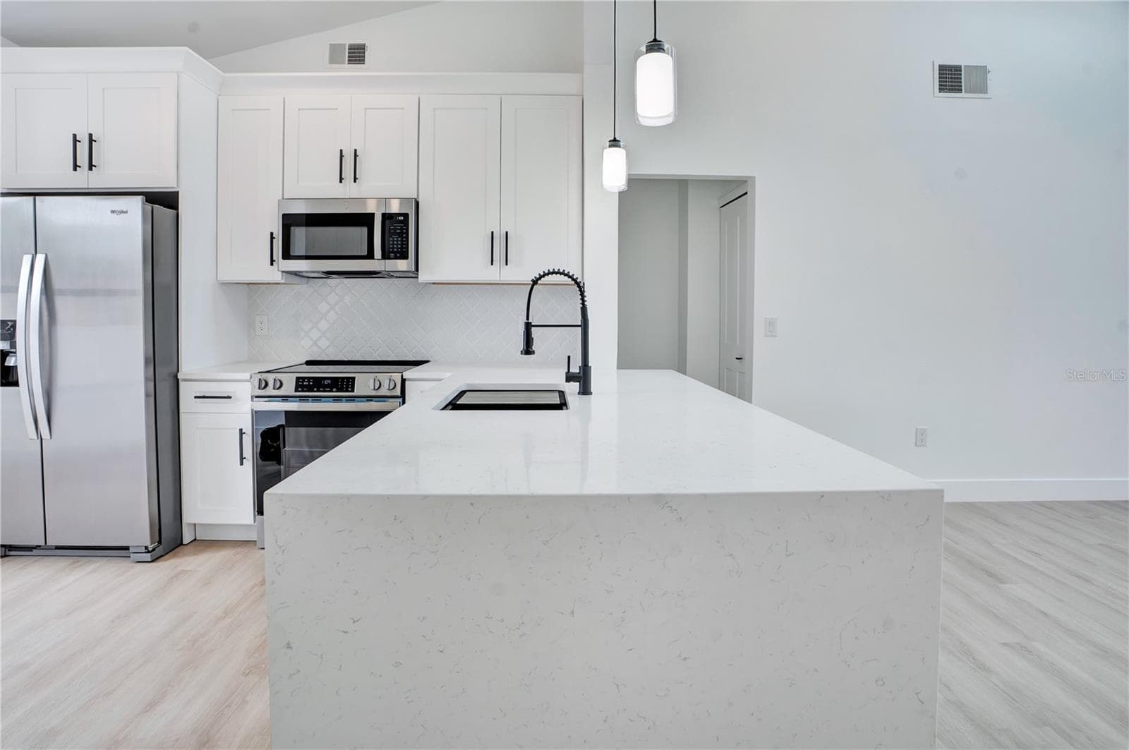 Stunning quartz waterfall-edge countertop creates a beautiful focal point in the redesigned kitchen. - 3012 S SEMORAN BLVD #G2, ORLANDO