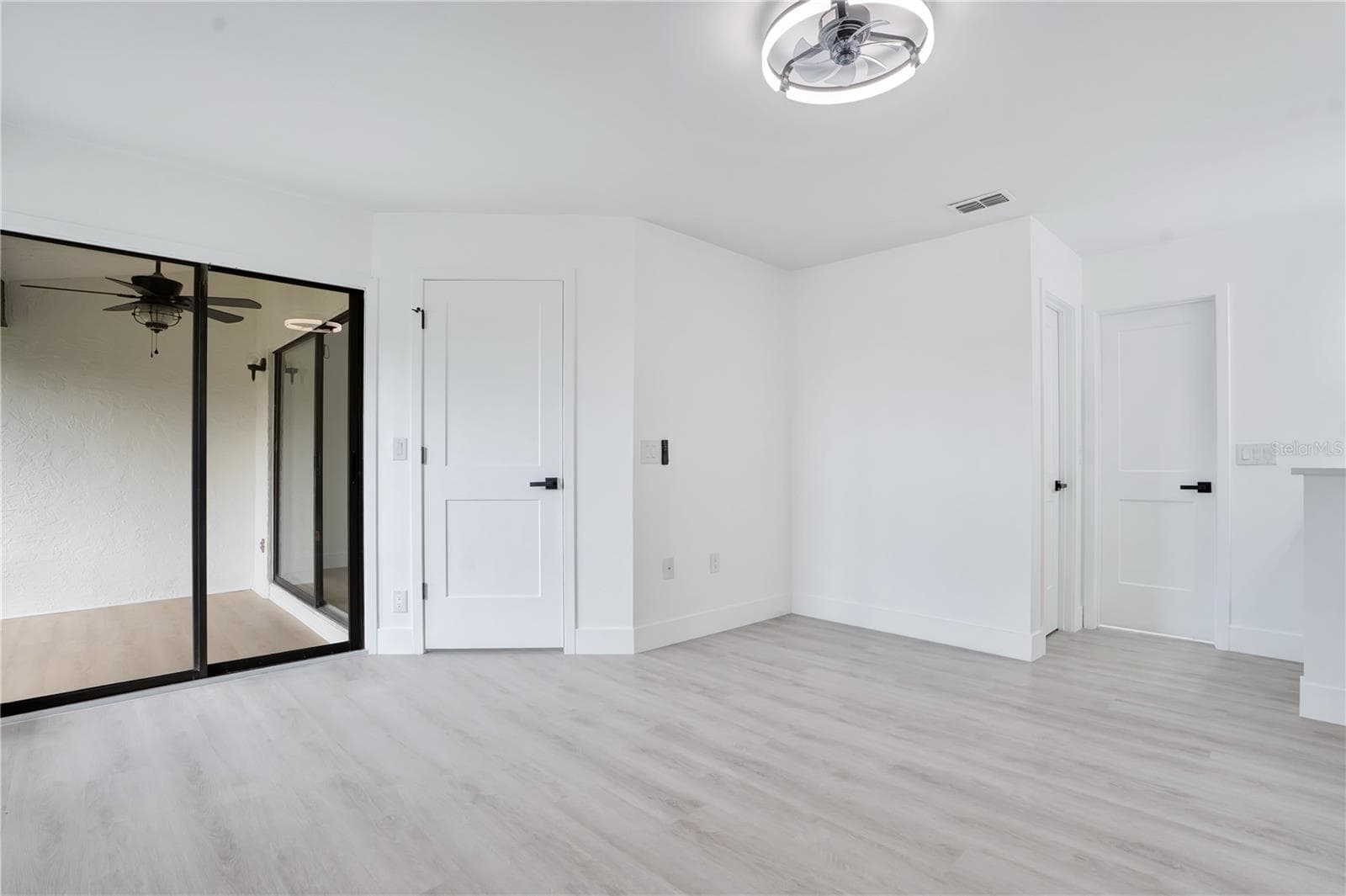 Spacious primary bedroom featuring brand-new flooring, ceiling fan and fresh modern finishes. - 3012 S SEMORAN BLVD #G2, ORLANDO