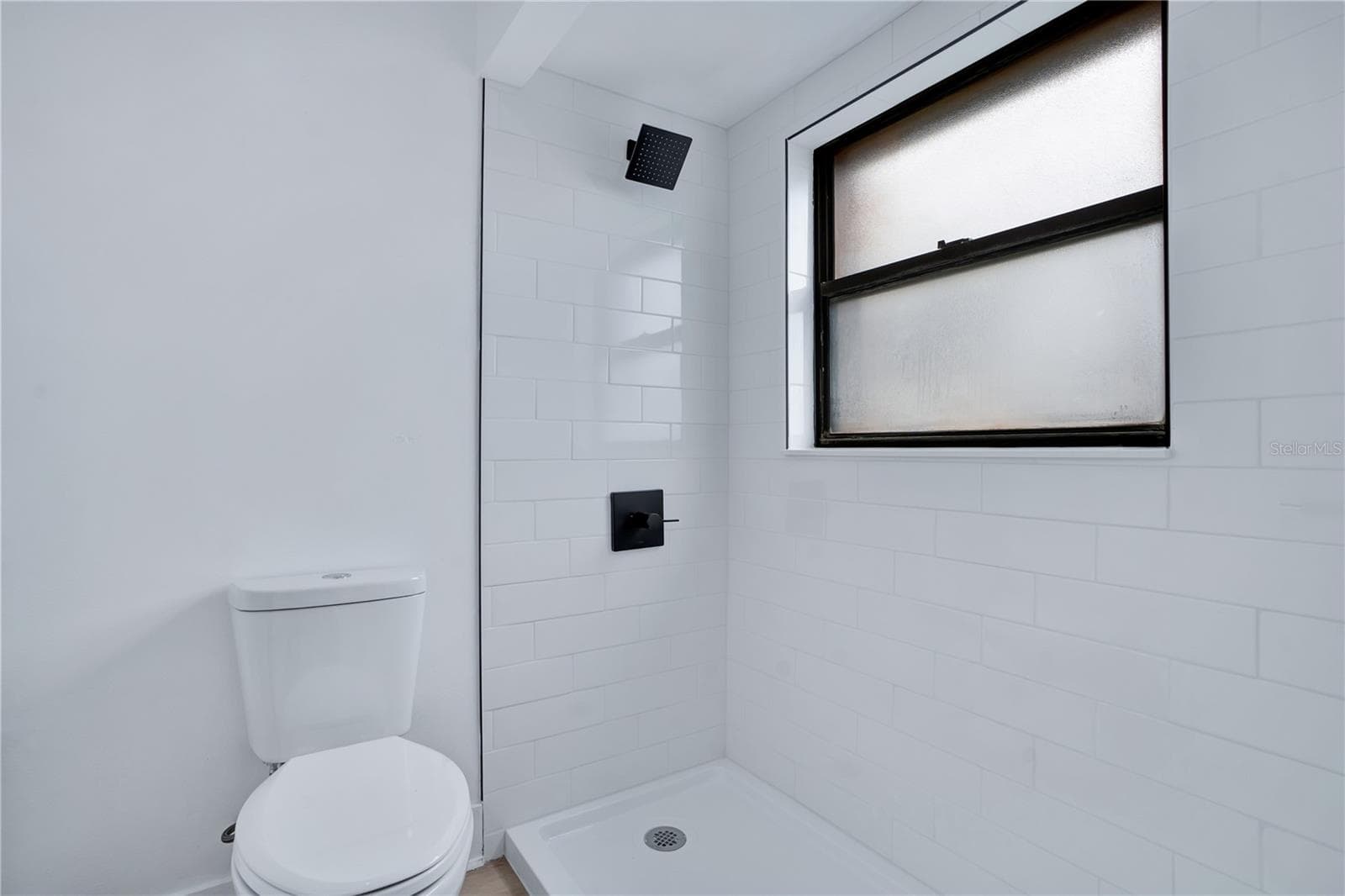 Sleek walk-in shower featuring contemporary tilework and modern black fixtures. - 3012 S SEMORAN BLVD #G2, ORLANDO