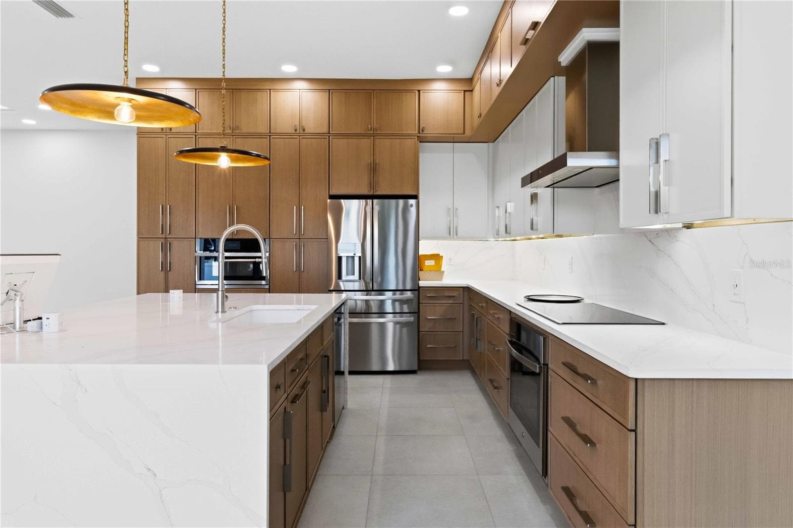 designer kitchen combines warmth and modern elegance with full-height wood cabinetry, quartz countertops, stainless-steel appliances, generous storage, and an oversized waterfall-edge island - 104 S MAKI RD, PLANT CITY