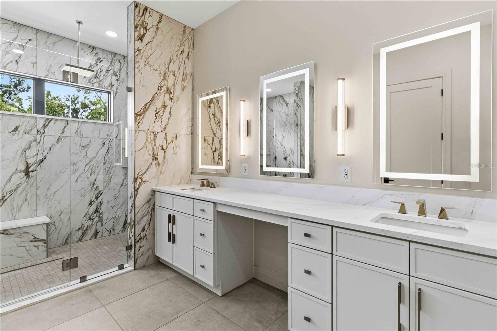 Floor-to-ceiling marble tile surrounds the oversized glass-enclosed shower, while a freestanding soaking tub, dual vanities, illuminated mirrors, contemporary fixtures, and a dedicated makeup station bring boutique-hotel luxury into everyday life - 104 S MAKI RD, PLANT CITY