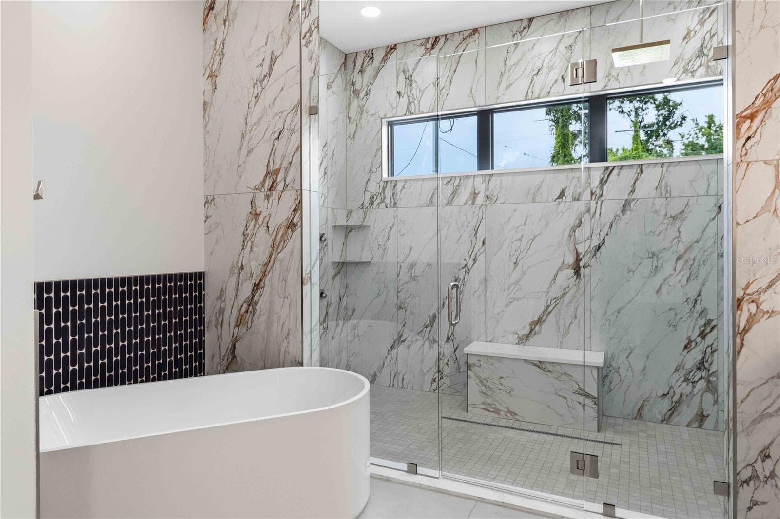 Floor-to-ceiling marble tile surrounds the oversized glass-enclosed shower, while a freestanding soaking tub, dual vanities, illuminated mirrors, contemporary fixtures, and a dedicated makeup station bring boutique-hotel luxury into everyday life - 104 S MAKI RD, PLANT CITY