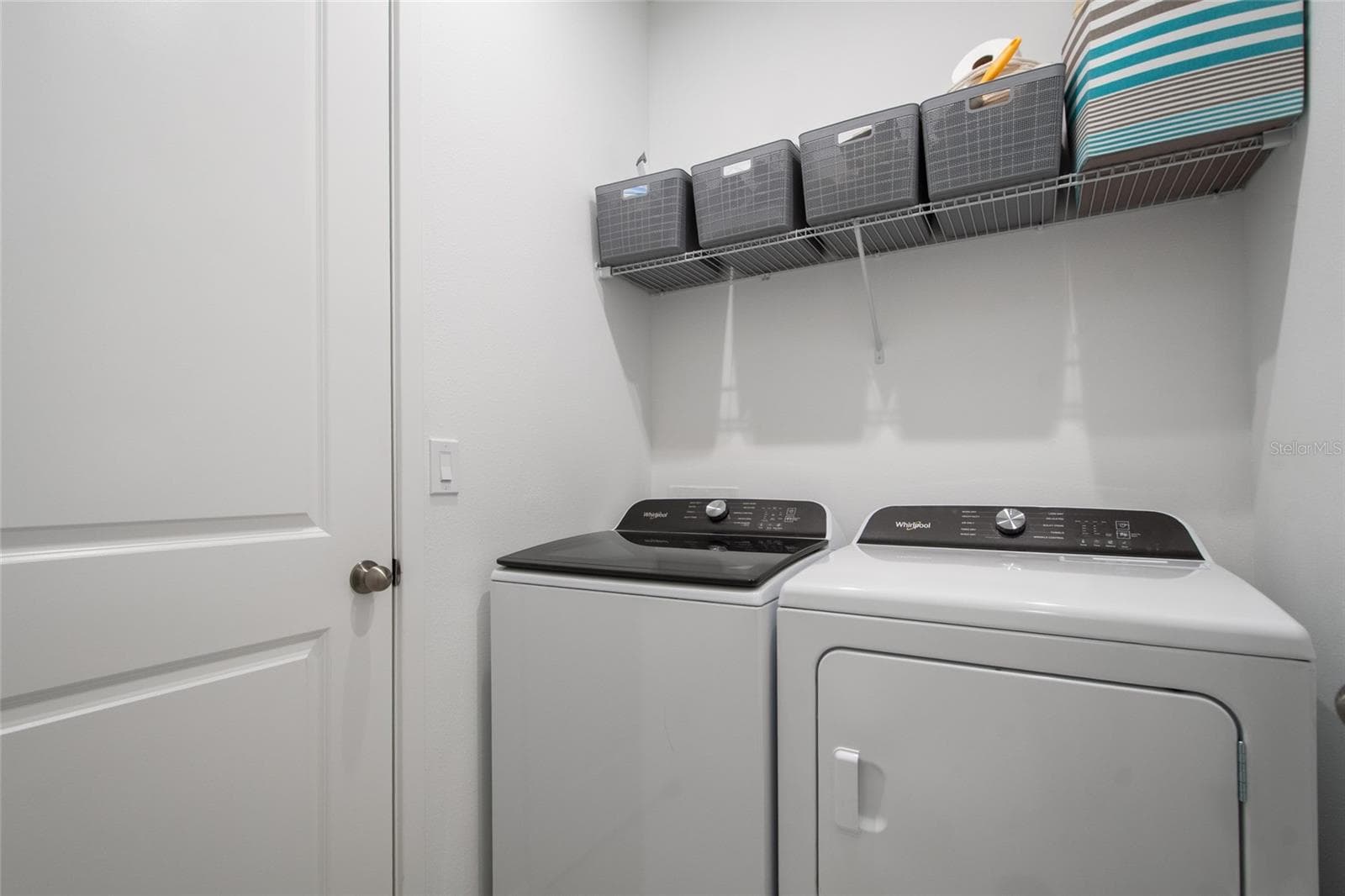 In the same hallway as Bedroom 4 and Bathroom 3 is the laundry room complete with washer and dryer hook up and shelving for laundry essentials. - 2685 SWEET ACACIA DR, CLERMONT