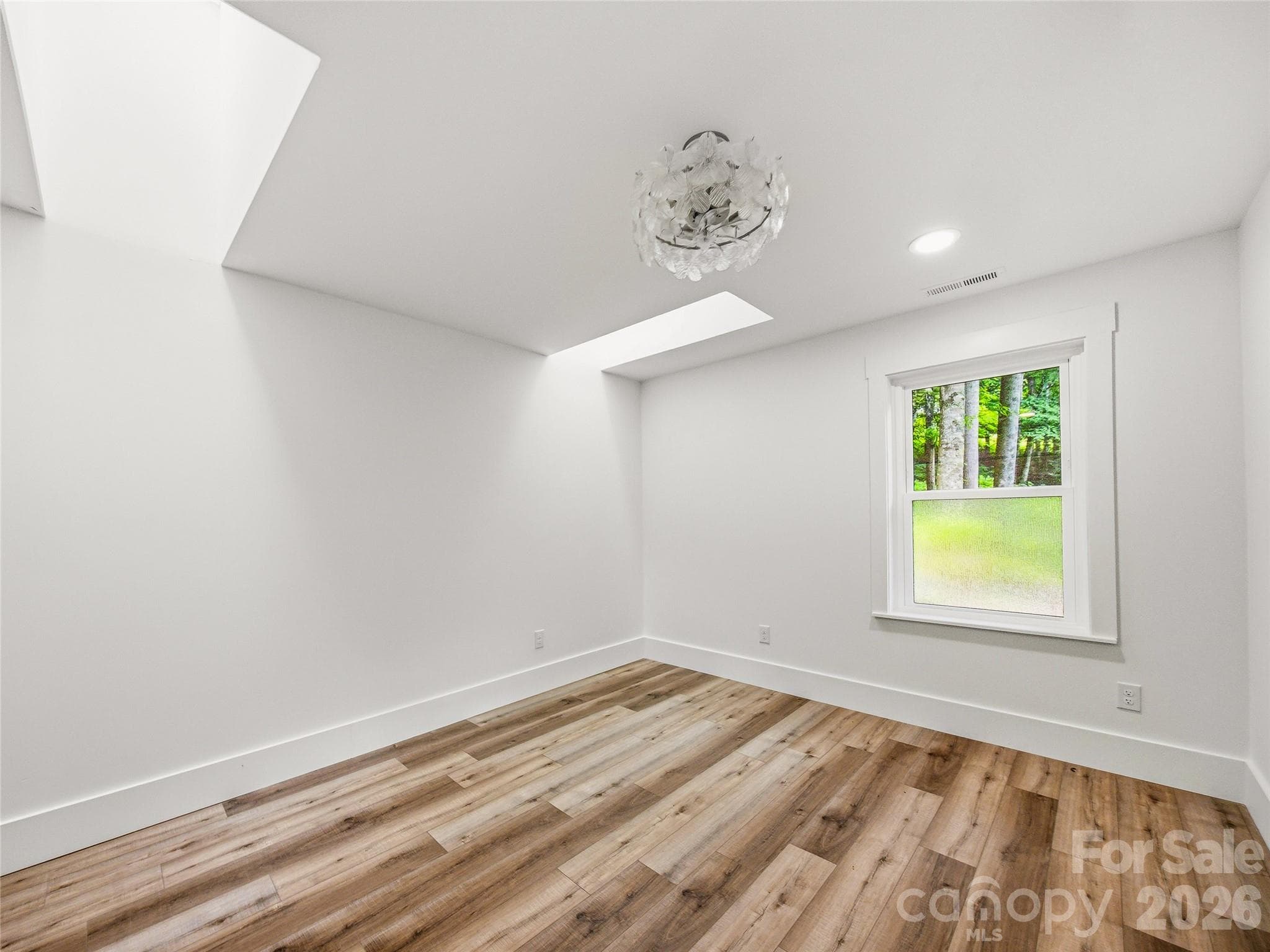 Bright first-floor bedroom featuring two closets, skylights, and peaceful wooded views. - 81 Summer Trees Lane, Burnsville
