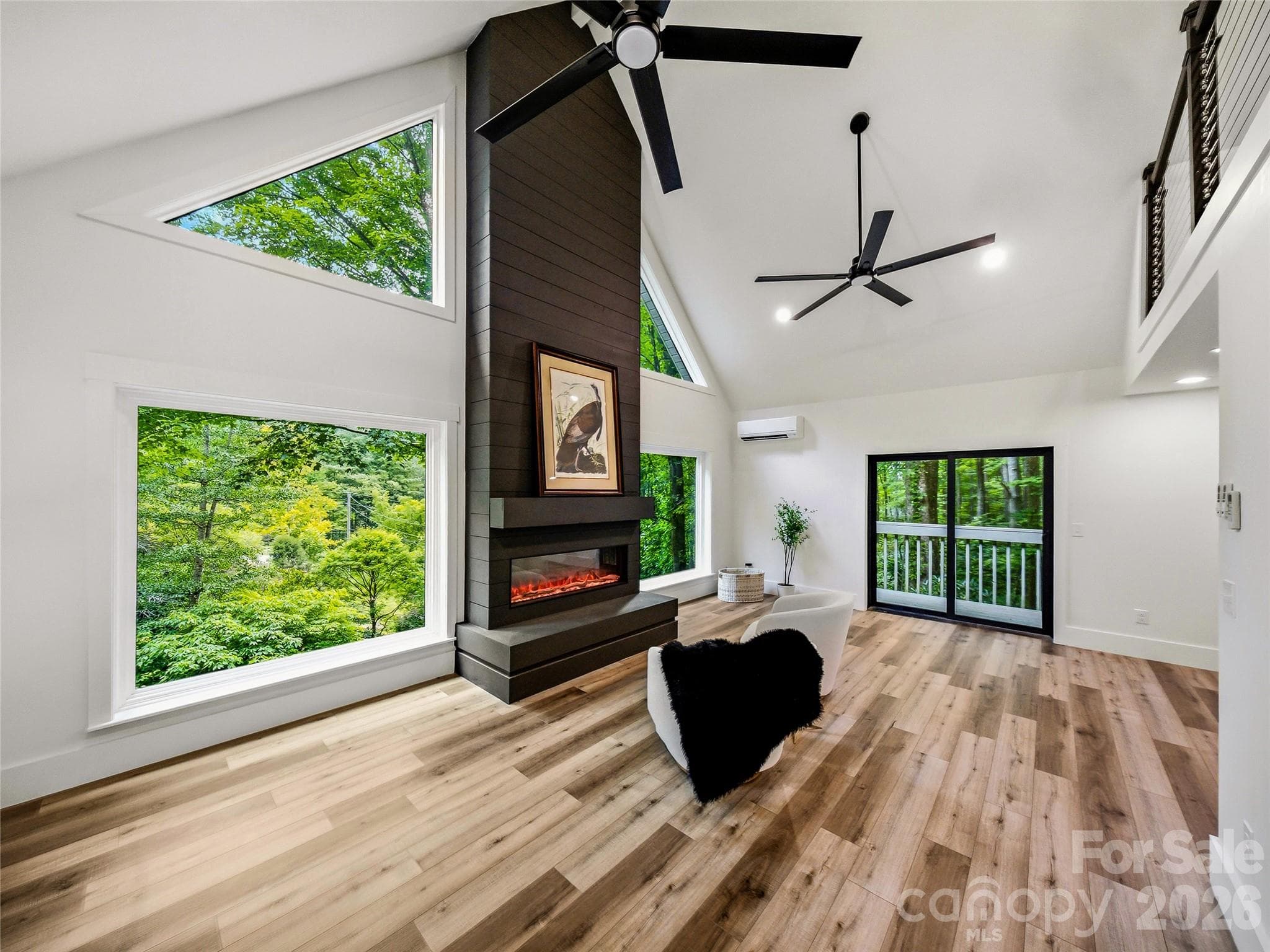 Spacious living area featuring a custom electric fireplace, expansive forest views, and direct access to the private deck. - 81 Summer Trees Lane, Burnsville