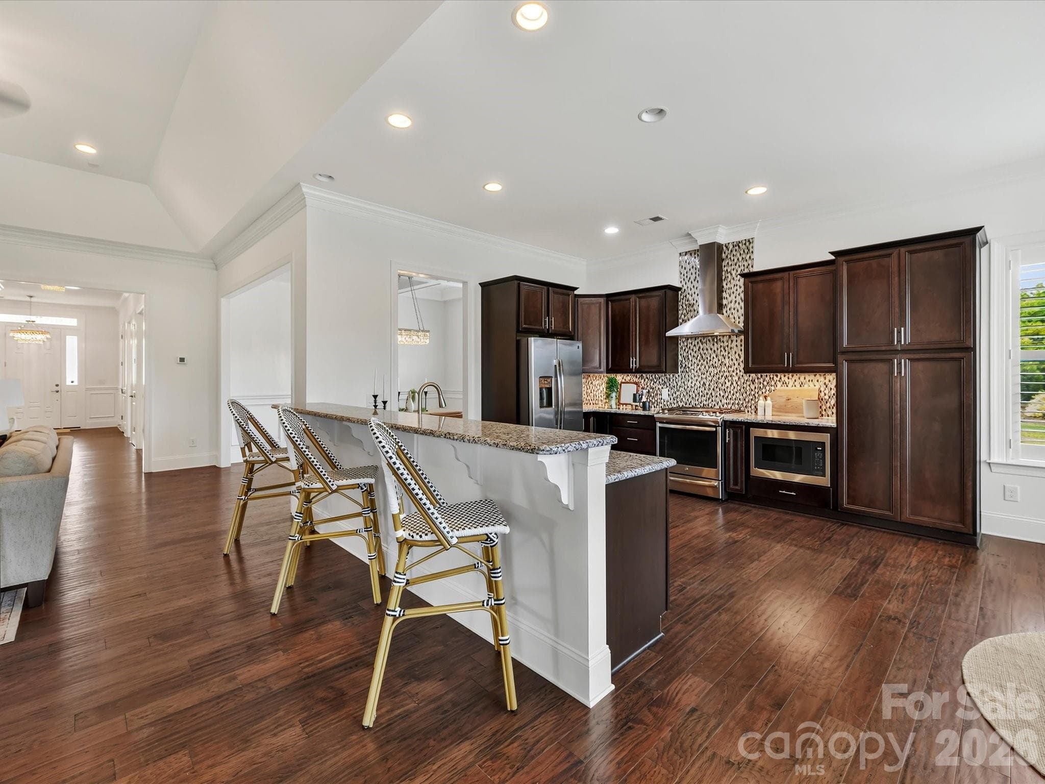 Spacious kitchen features abundant cabinetry, granite countertops, stainless steel appliances, a decorative tile backsplash and an oversized breakfast bar with seating. - 13003 Riley Grace Lane, Cornelius