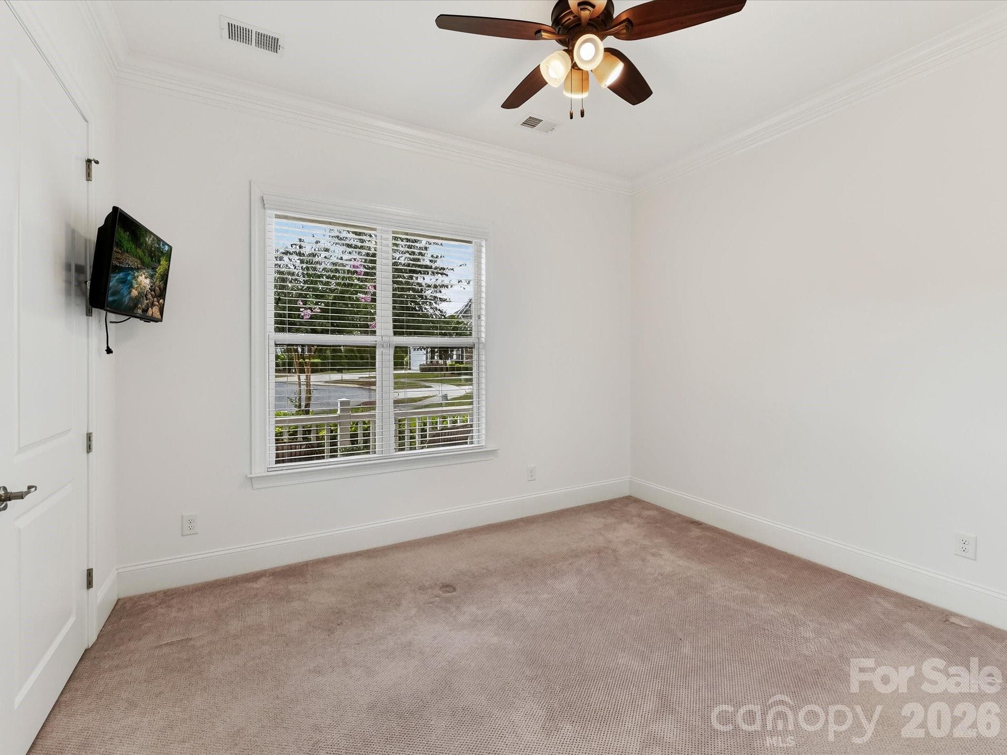 Main-level guest suite offers abundant natural light, crown molding, neutral carpeting, and flexibility for guests or additional living space. - 13003 Riley Grace Lane, Cornelius