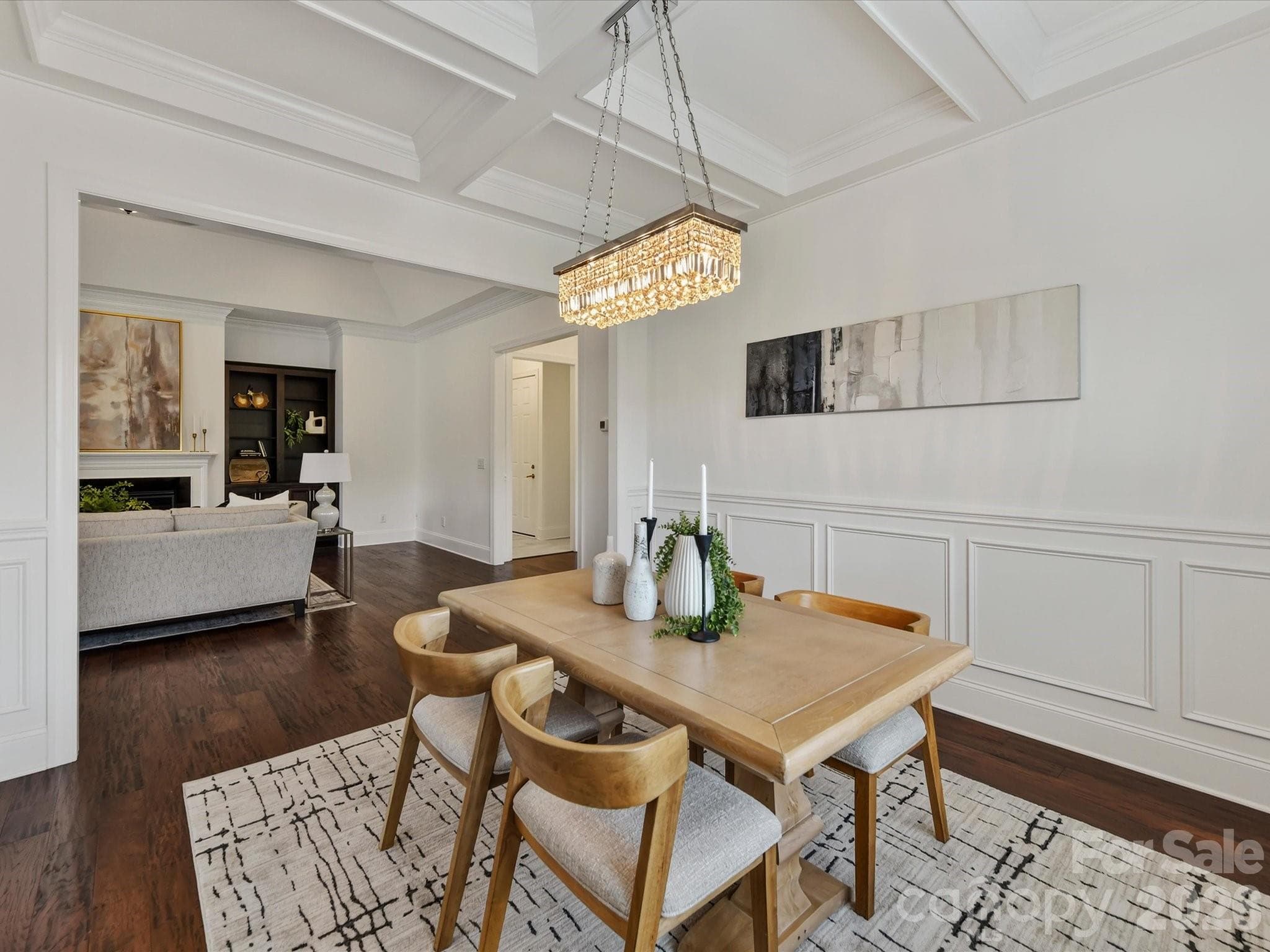 Elegant dining room features beautiful flooring, detailed wainscoting, a coffered ceiling and statement lighting with an open flow to the main living areas. - 13003 Riley Grace Lane, Cornelius