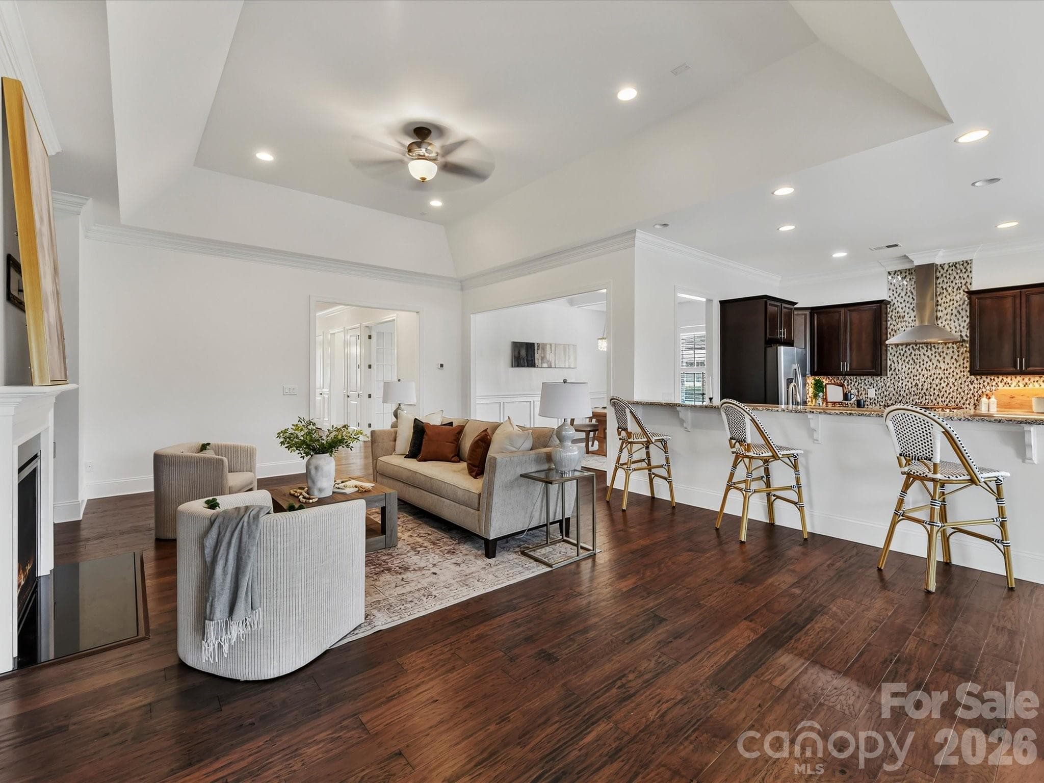 Open-concept Great Room and kitchen feature soaring ceilings, a cozy gas log fireplace, and an expansive breakfast bar that creates an effortless flow for everyday living and entertaining. - 13003 Riley Grace Lane, Cornelius