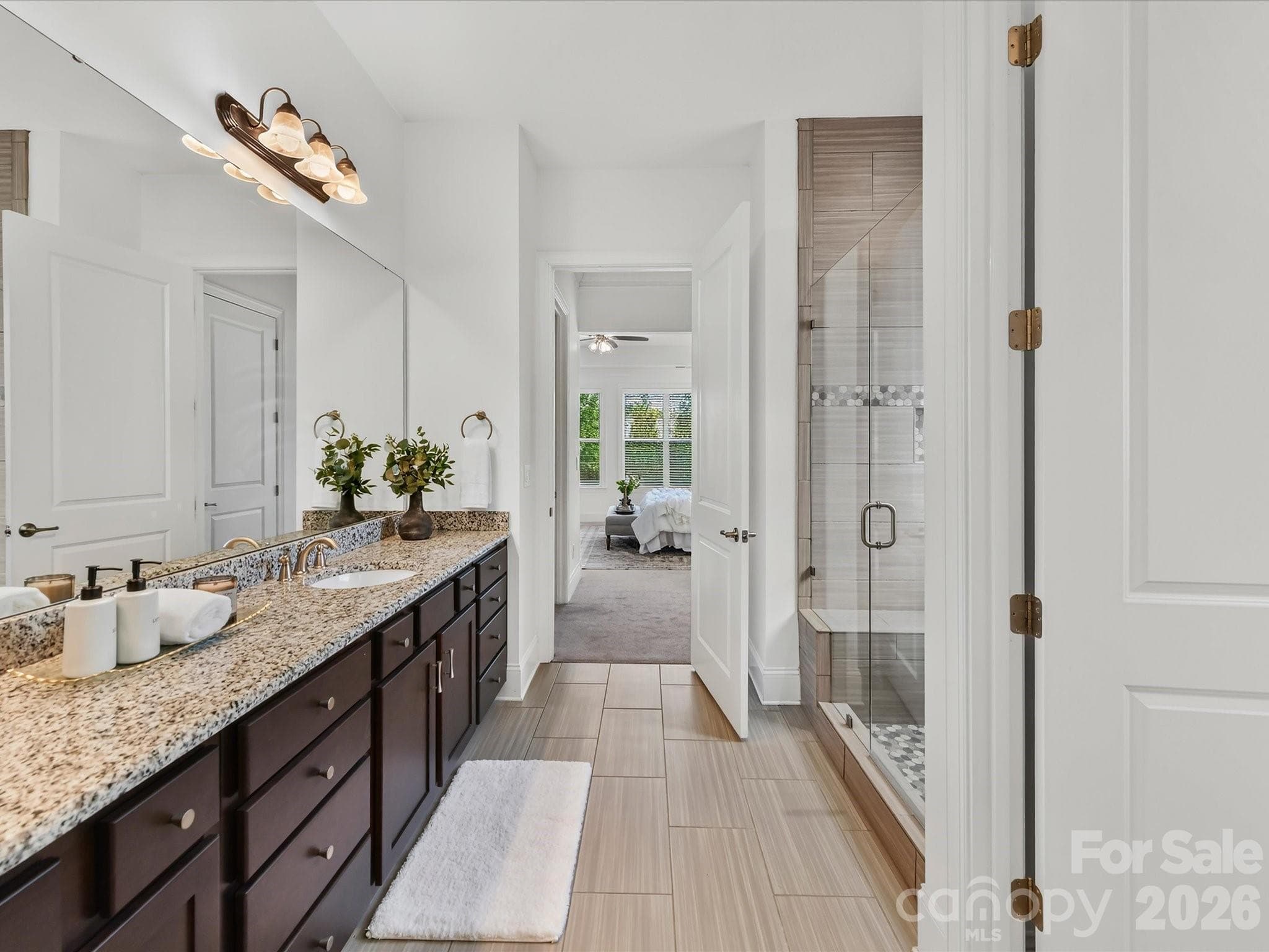 Spacious primary bath features a long dual-sink granite vanity, tiled walk-in shower, and separate water closet. - 13003 Riley Grace Lane, Cornelius
