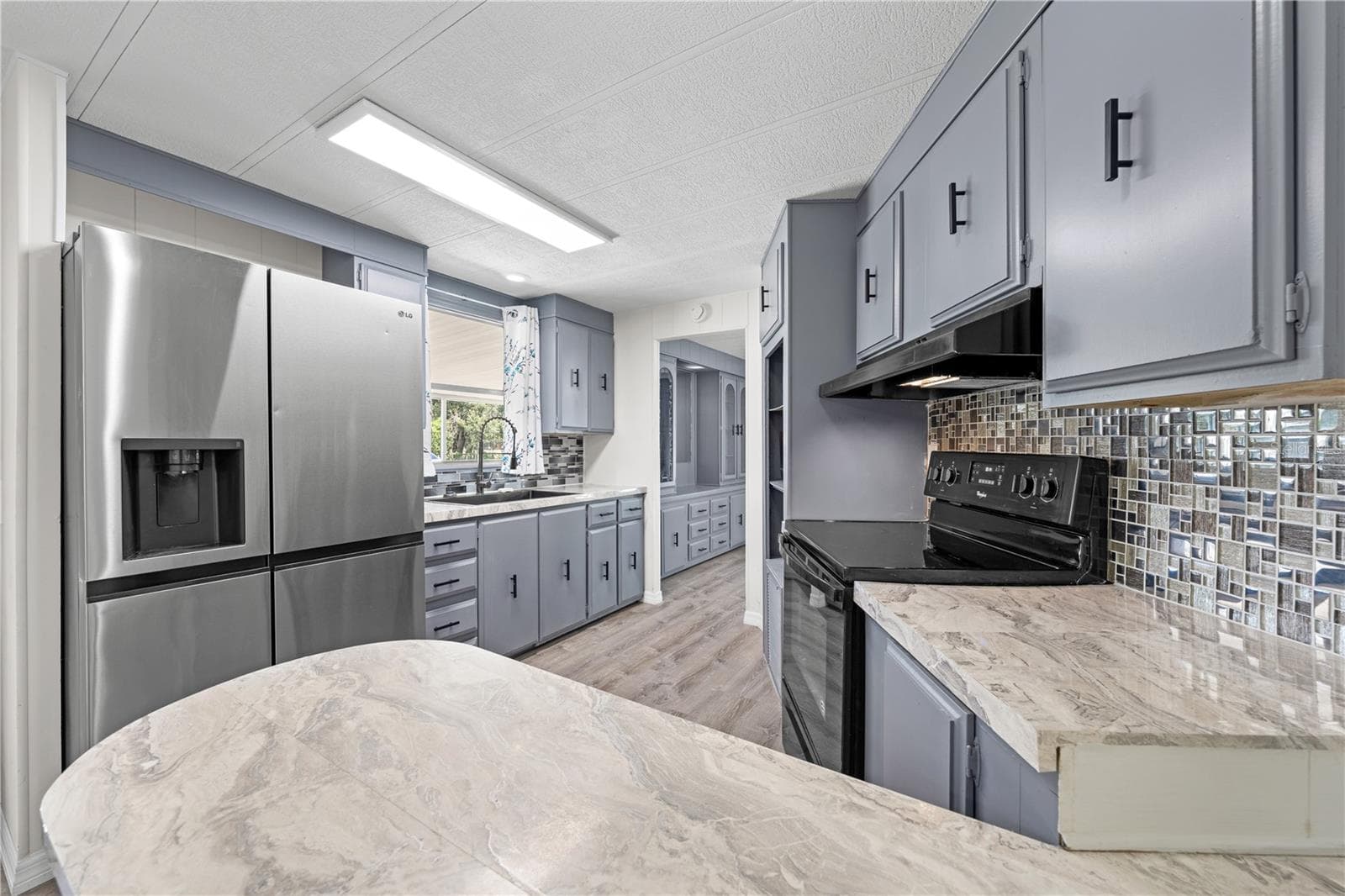 Freshly painted kitchen cabinets and new backsplash tile coupled with a full size stainless steel fridge highlight this kitchen. - 5601 LAKE LIZZIE DR, ST CLOUD