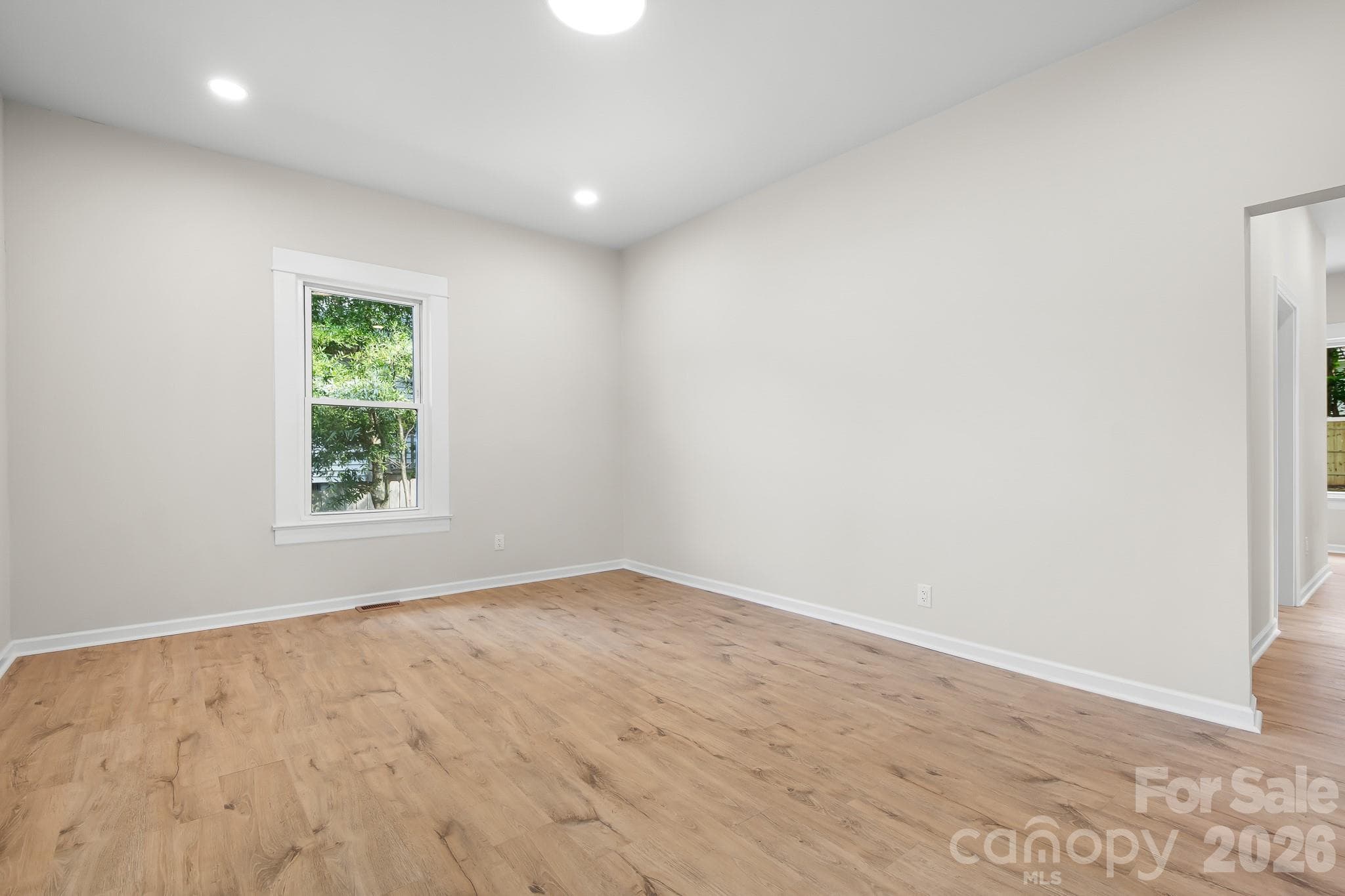 Bright, spacious living room with warm flooring and natural light. - 104 1st Avenue, China Grove