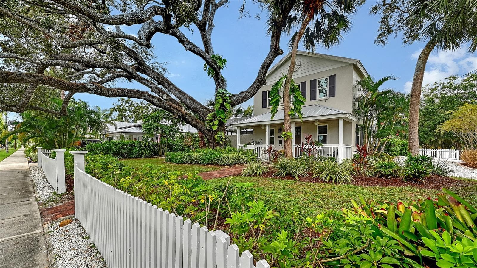 Elegant front elevation framed by a magnificent mature oak and lush tropical landscaping creates a sophisticated first impression. - 1685 6TH ST, SARASOTA