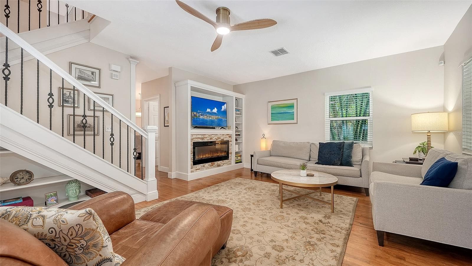 Bright, sophisticated living room features rich hardwood floors, an electric fireplace, custom built-ins, and refined coastal-inspired furnishings. - 1685 6TH ST, SARASOTA
