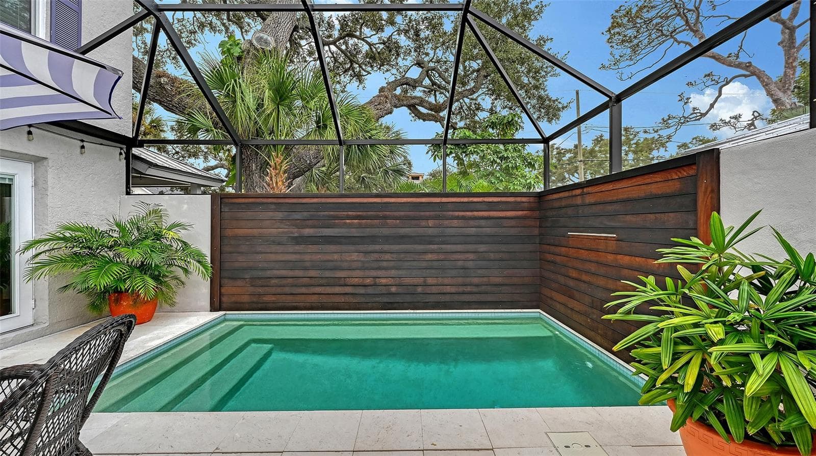 Private screened pool retreat creates an elevated resort-style setting surrounded by lush tropical landscaping and custom wood privacy fencing. - 1685 6TH ST, SARASOTA