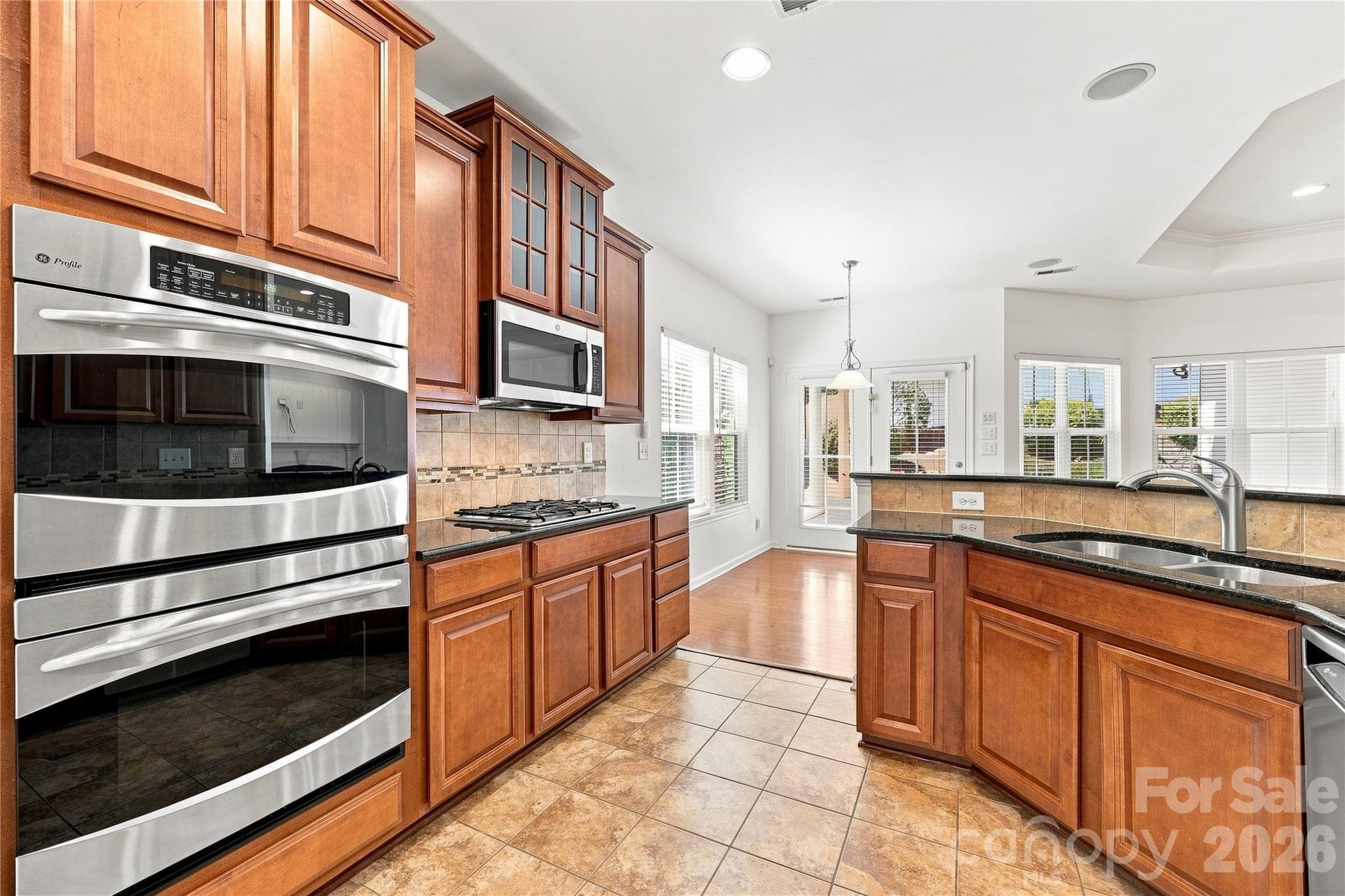 Kitchen with 32 in. cabinets, stainless steel appliances, gas stove top, double ovens, microwave, granite counters, tile backsplash and newer refrigerator - 593 Harrison Drive NW, Concord