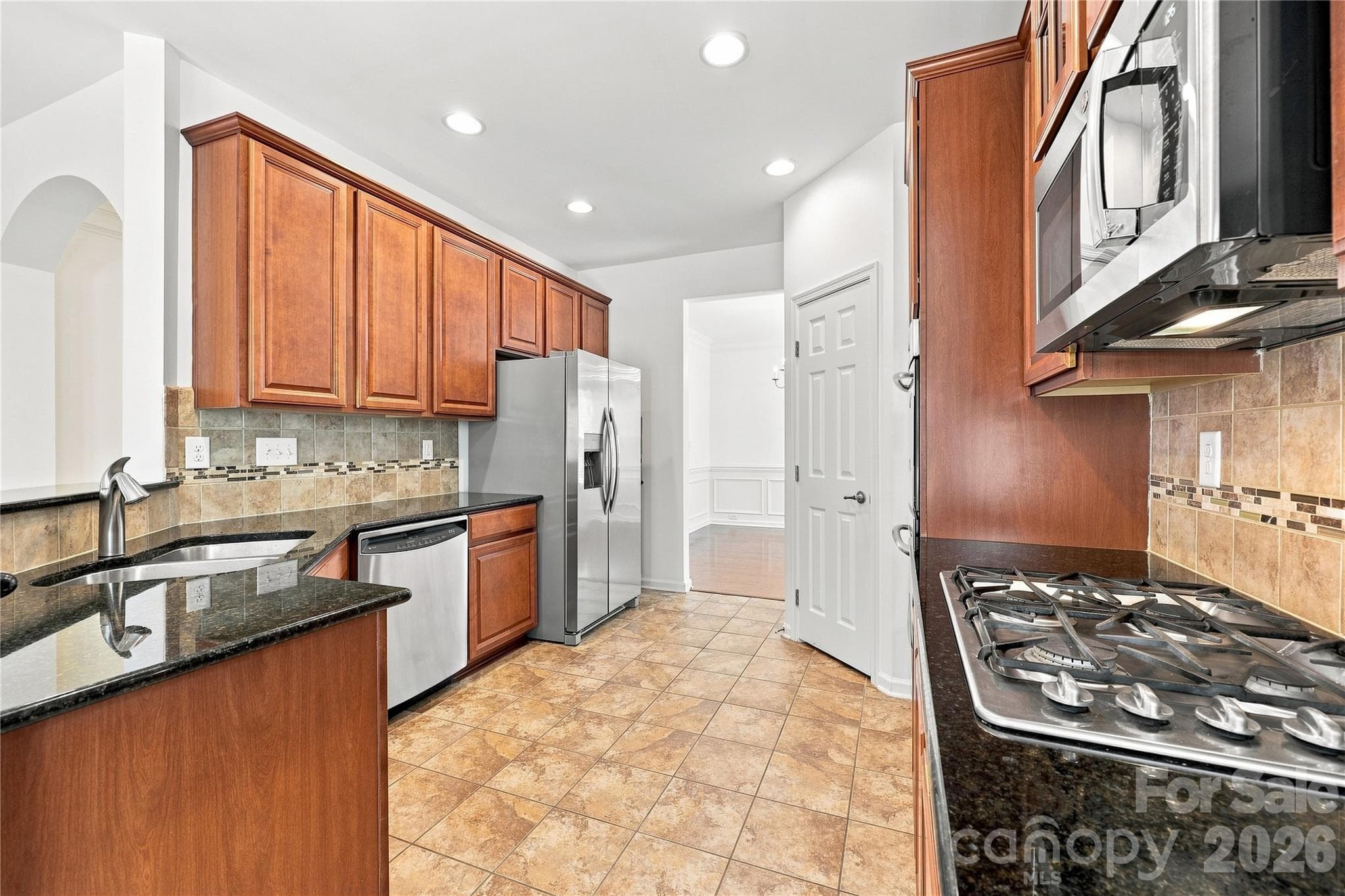 Kitchen with 32 in. cabinets, stainless steel appliances, gas stove top, double ovens, microwave, granite counters, tile backsplash and newer refrigerator - 593 Harrison Drive NW, Concord