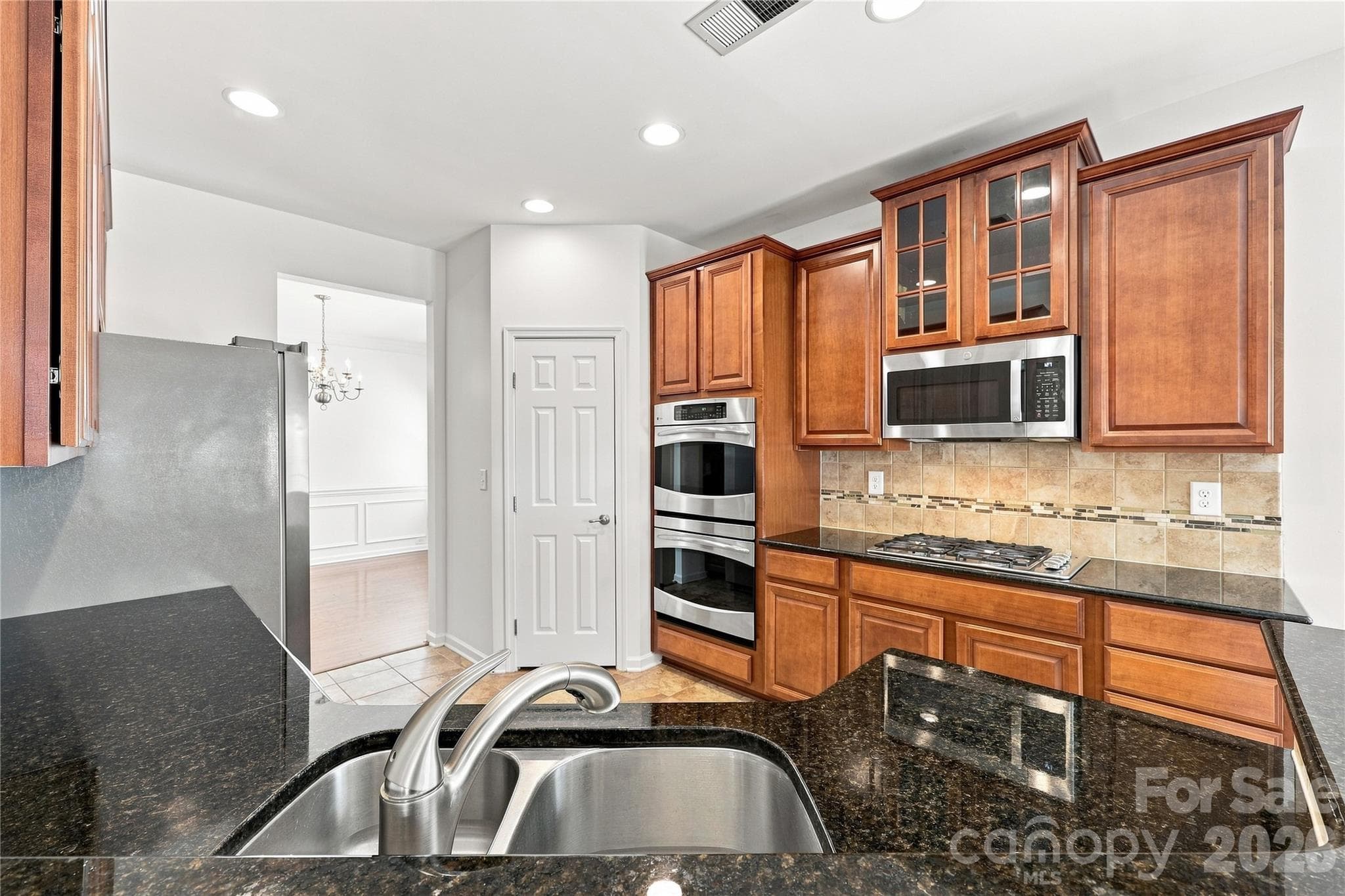 Kitchen with 32 in. cabinets, stainless steel appliances, gas stove top, double ovens, microwave, granite counters, tile backsplash and newer refrigerator - 593 Harrison Drive NW, Concord