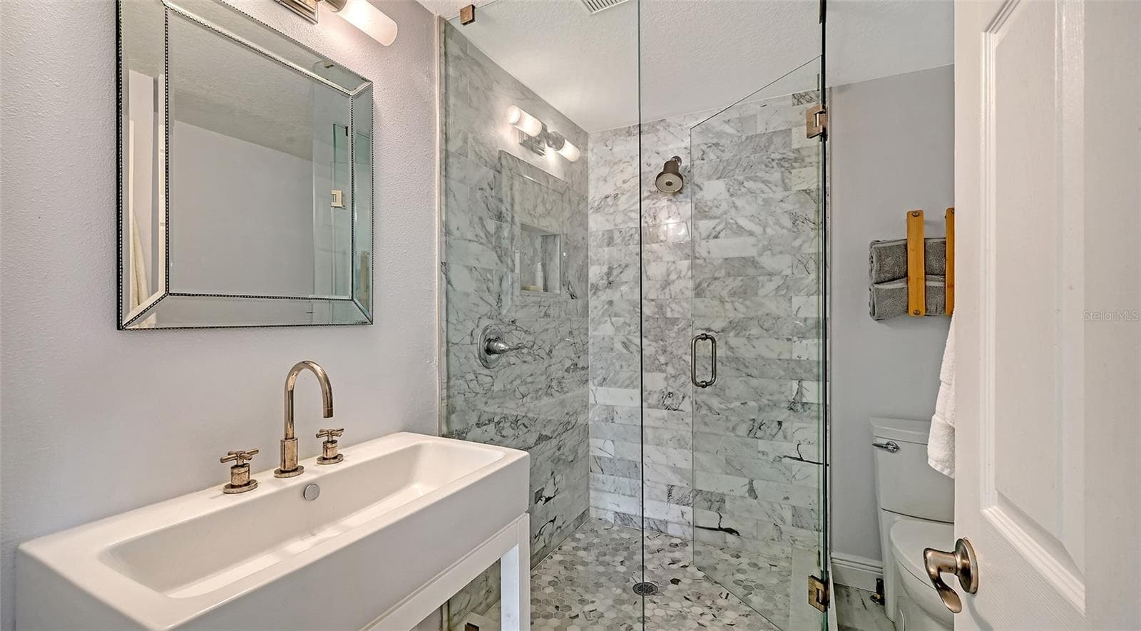 Renovated en-suite bathroom features a sophisticated walk-in glass shower, elegant vanity, and upscale finishes. - 1685 6TH ST, SARASOTA