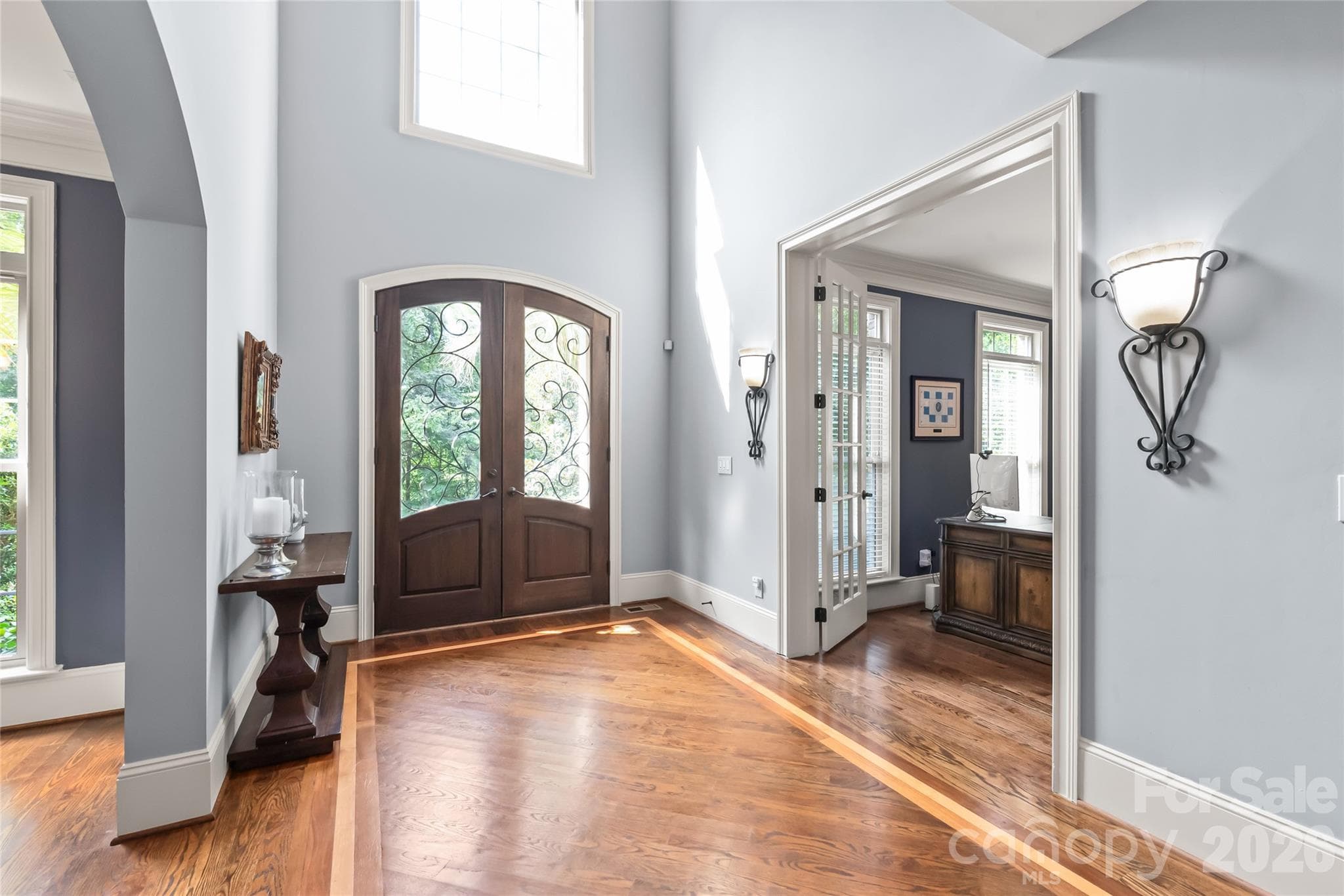 A grand two-story entryway framed by eight-foot double doors sets an imposing tone, opening up to rich hardwoods running throughout the home. - 7320 Summerlin Place, Charlotte
