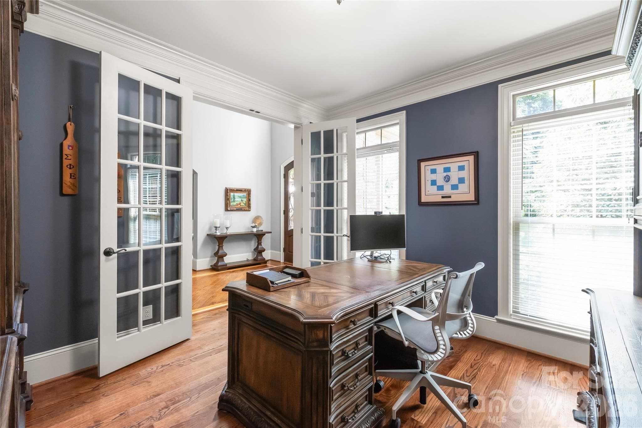An executive office framed by eight-foot French doors, heavy crown molding, and an abundance of warm natural light. - 7320 Summerlin Place, Charlotte