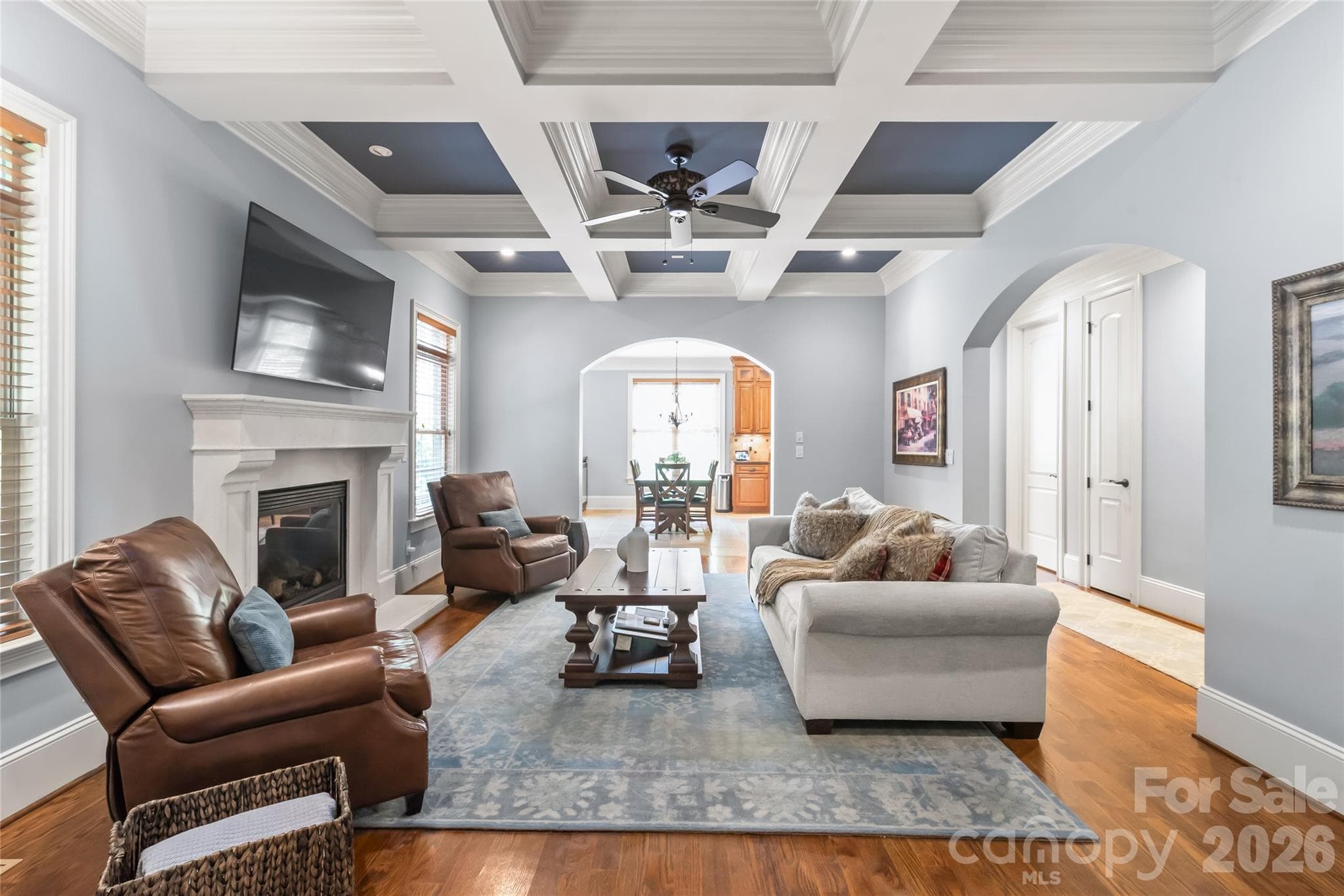A custom stone fireplace, rich coffered ceilings, and dramatic arched entryways serve as the centerpieces of this inviting family room. - 7320 Summerlin Place, Charlotte