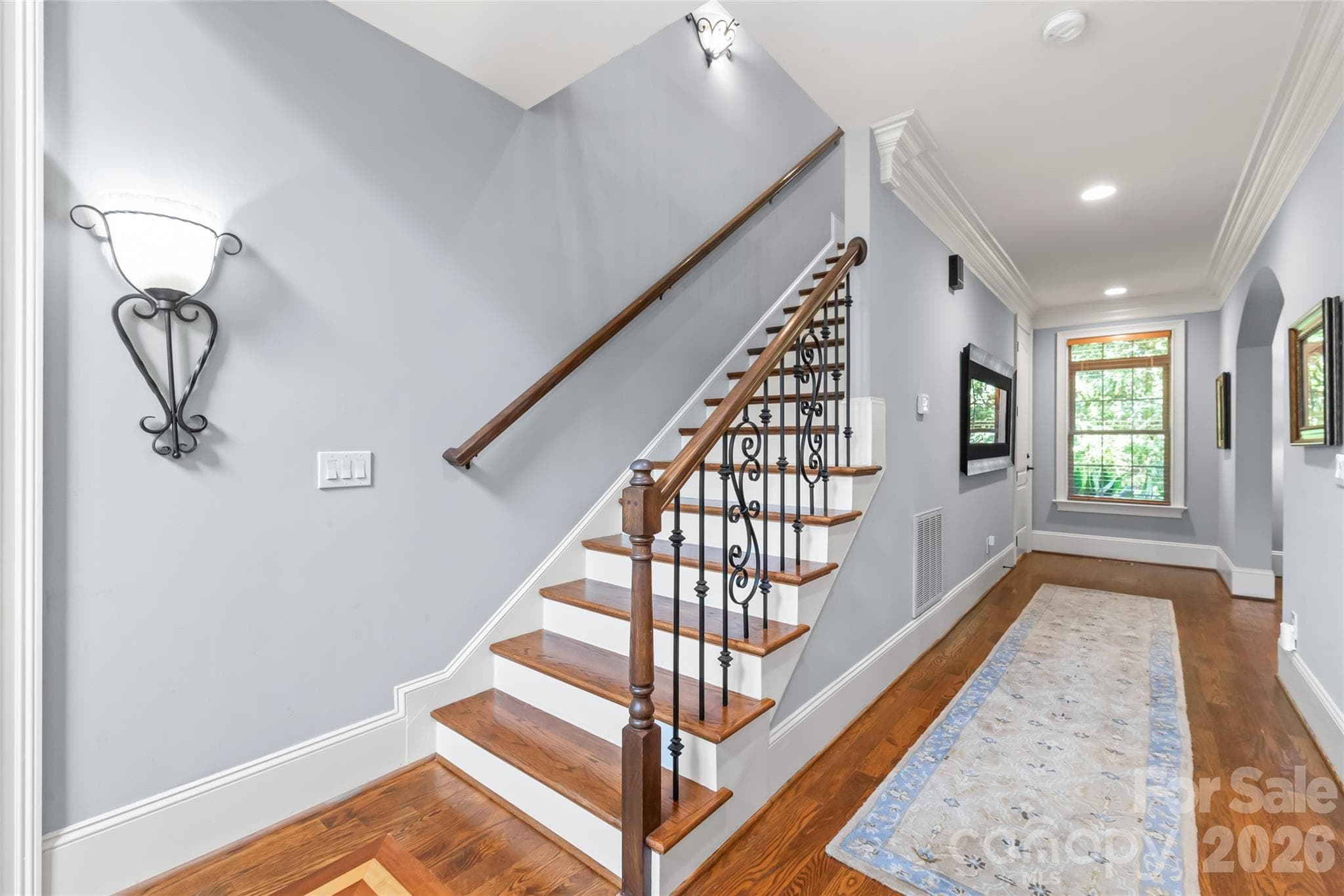 Stunning hardwood stairs complemented by classic iron spindles bring timeless structure and style to the home's entry. - 7320 Summerlin Place, Charlotte