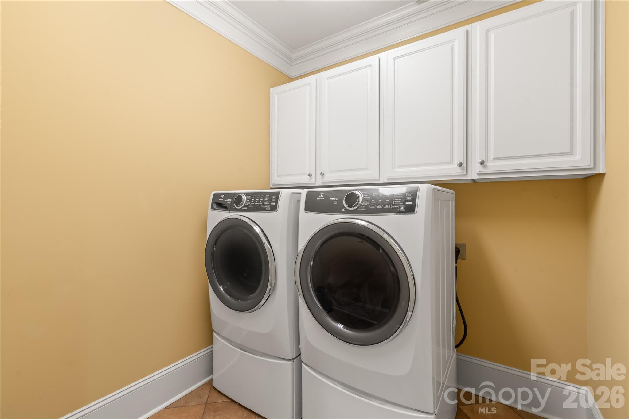 A functional laundry room featuring built-in upper cabinets for seamless, out-of-sight storage. - 7320 Summerlin Place, Charlotte