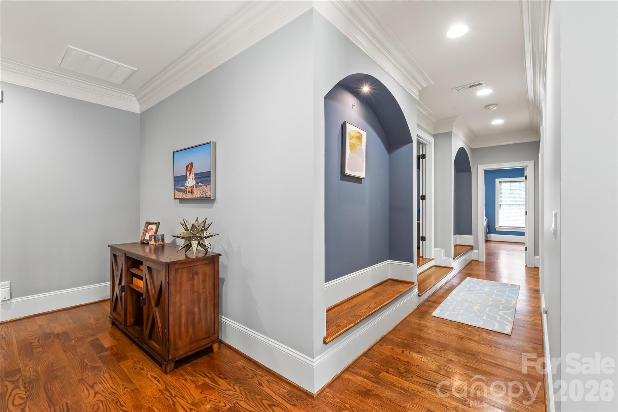 Stunning hardwood floors extend through the second-floor hallway, highlighted by recessed lighting, elegant arches, and detailed trim molding. - 7320 Summerlin Place, Charlotte