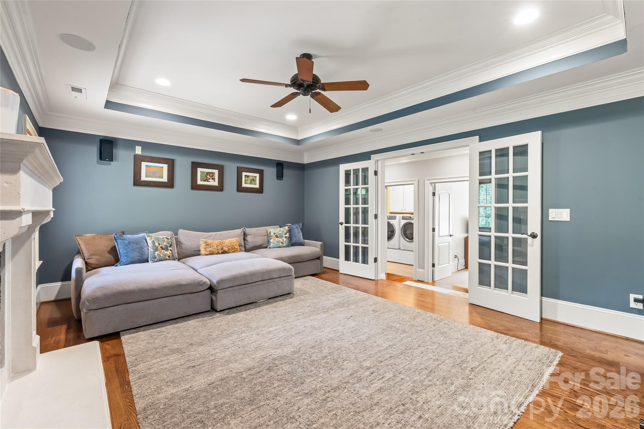 French doors open to a spacious bonus room featuring a tray ceiling, rich hardwood floors, and a dramatic second stone fireplace. - 7320 Summerlin Place, Charlotte