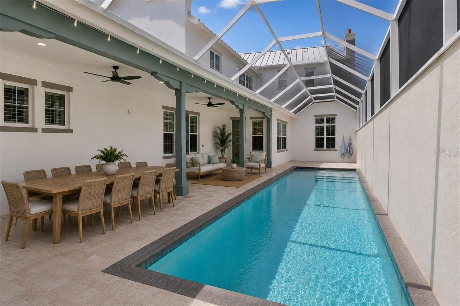 Virtually staged approximately 70-foot pool deck featuring covered outdoor dining, a lounge area, tanning space, and direct access to the main-level primary suite - 4024 11TH STREET CT W, PALMETTO