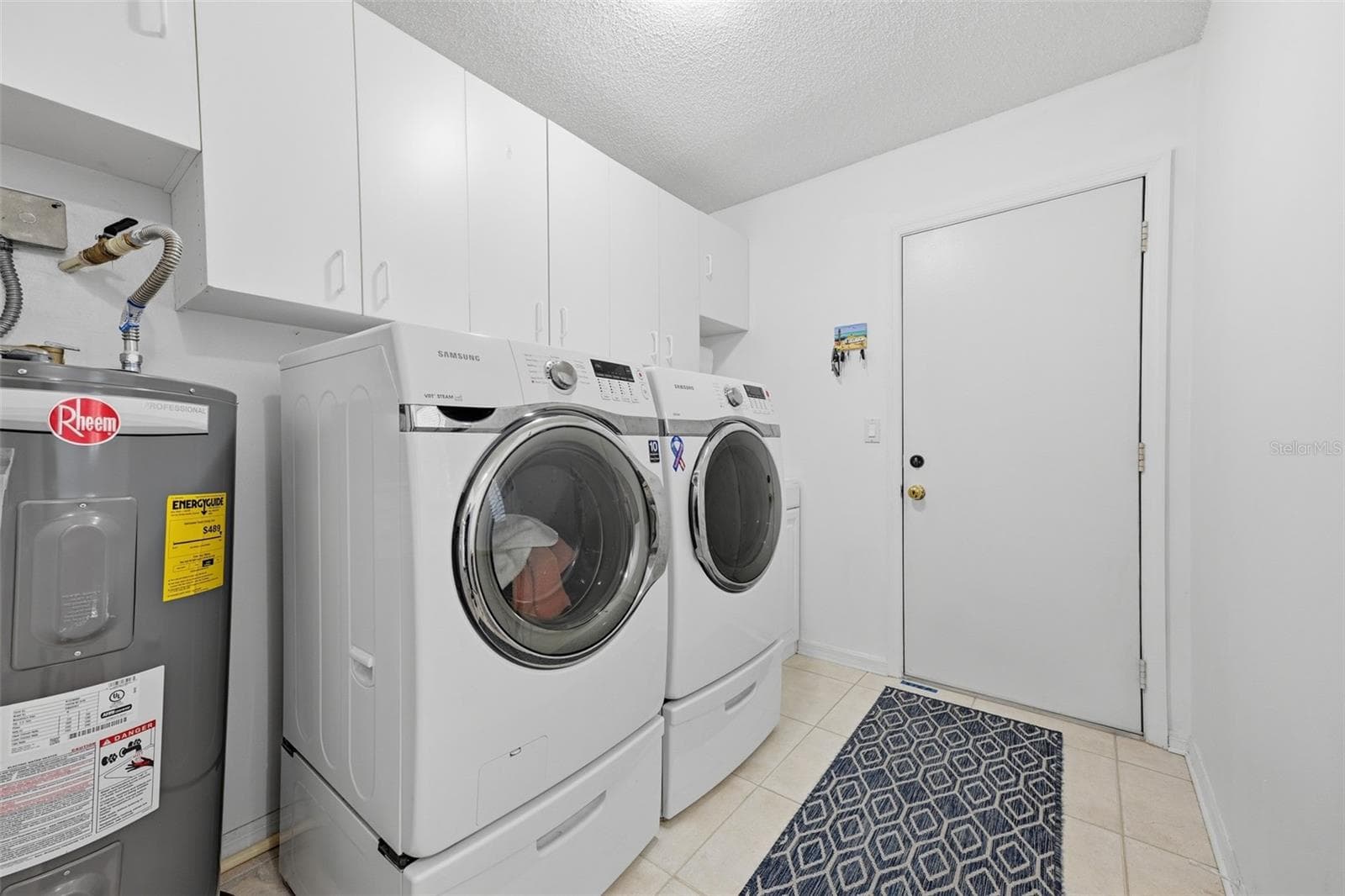 LAUNDRY ROOM WITH FRONT LOAD WASHER/DRYER, NEWER HOT WATER HEATER, CABINETS. - 1803 NEW BEDFORD DR, SUN CITY CENTER