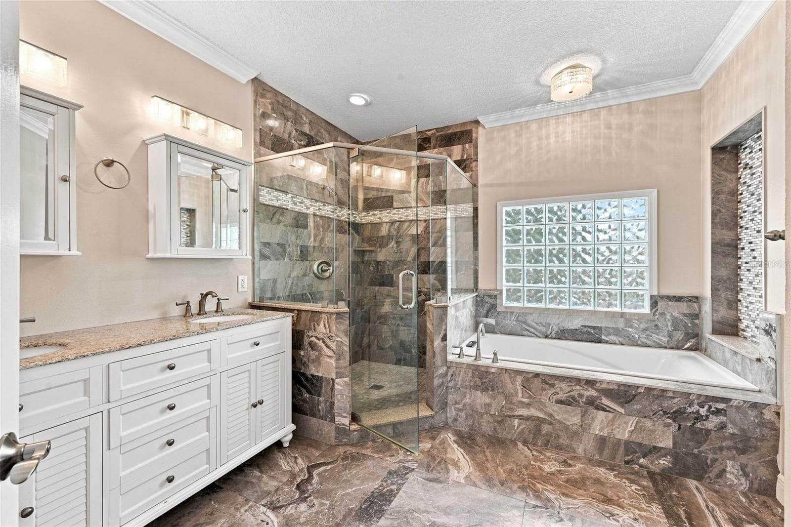 Spacious Primary En-Suite Bathroom features dual vanities, separate soaking tub, walk-in shower, decorative tile, and abundant natural light. - 1349 VALLEY PINE CIR, APOPKA