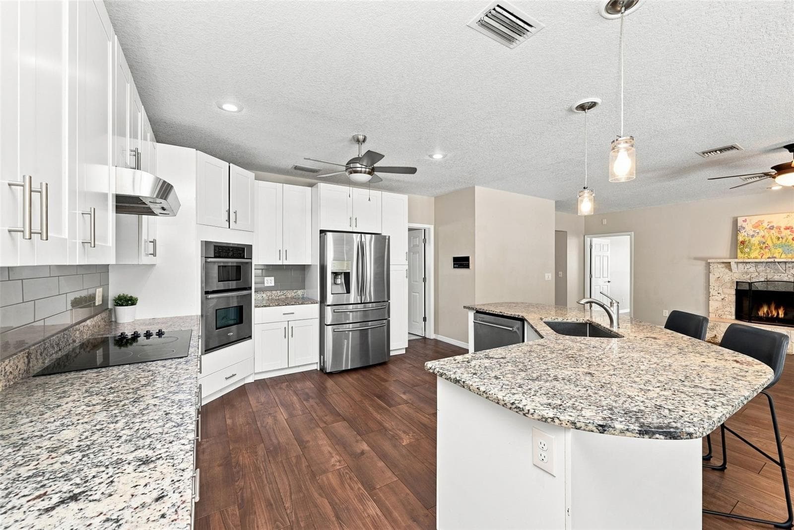 Open-Concept Kitchen & Living Space designed for entertaining with a large island, breakfast bar, granite countertops, and seamless flow throughout. - 1349 VALLEY PINE CIR, APOPKA