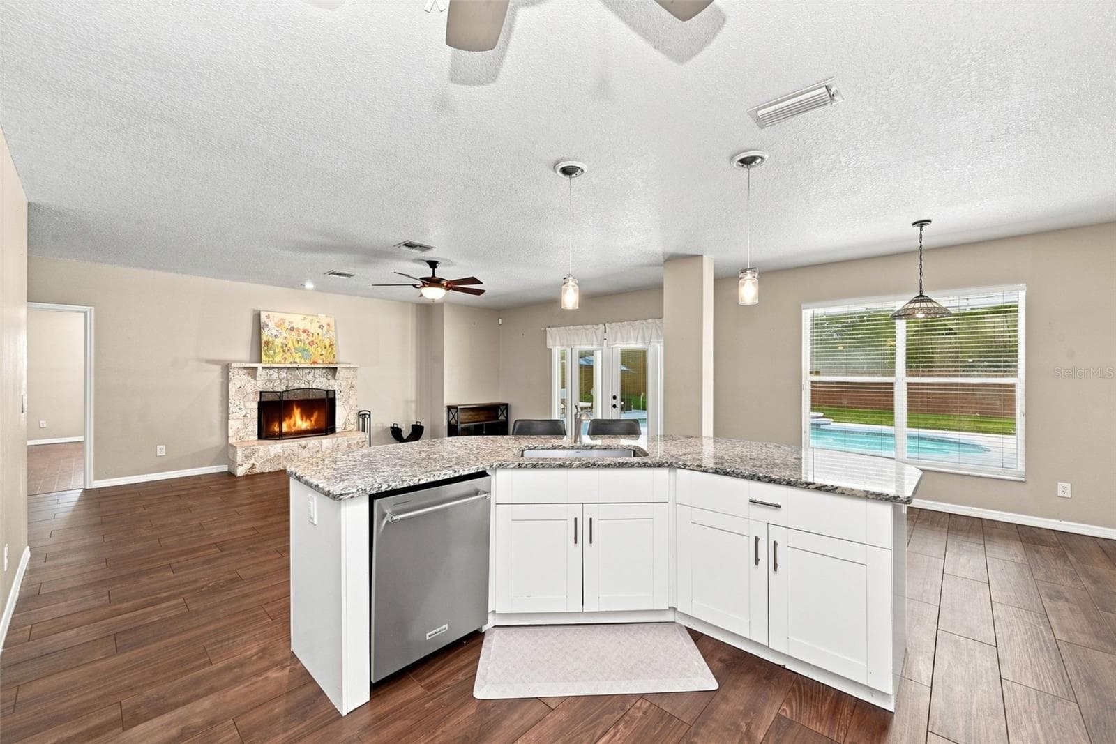 Light-Filled Open Kitchen & Family Room showcase the home’s spacious layout, granite countertops, white cabinetry, and inviting wood-burning fireplace. - 1349 VALLEY PINE CIR, APOPKA