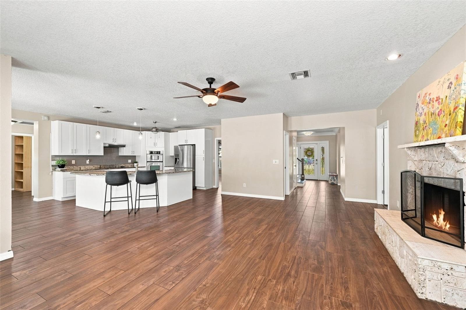 Open-Concept Kitchen & Family Room create an ideal gathering space with granite countertops, large island, wood flooring, and a wood-burning fireplace. - 1349 VALLEY PINE CIR, APOPKA