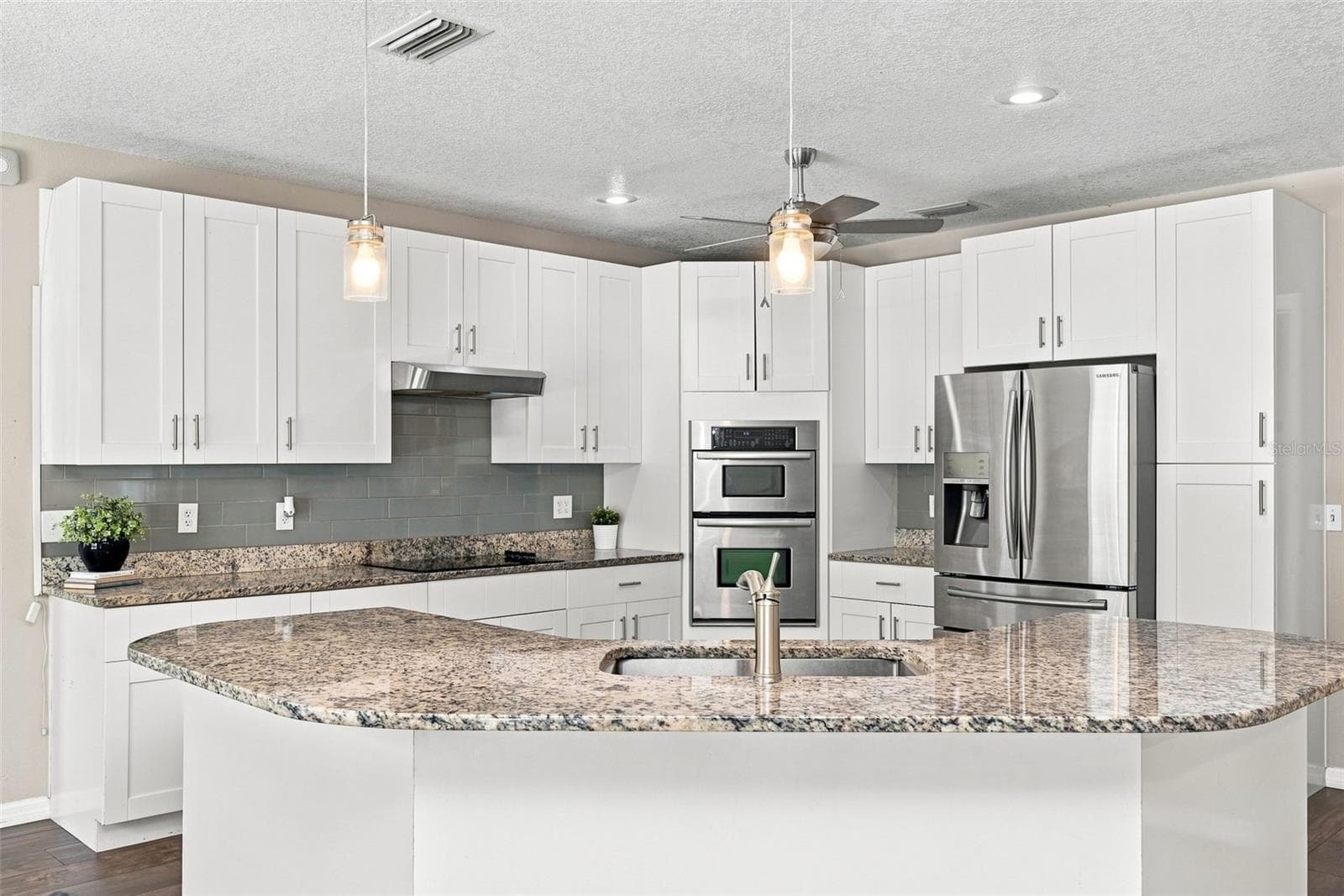 Updated Open-Concept Kitchen features white cabinetry, granite countertops, stainless-steel appliances, center island, breakfast bar, and abundant storage. - 1349 VALLEY PINE CIR, APOPKA