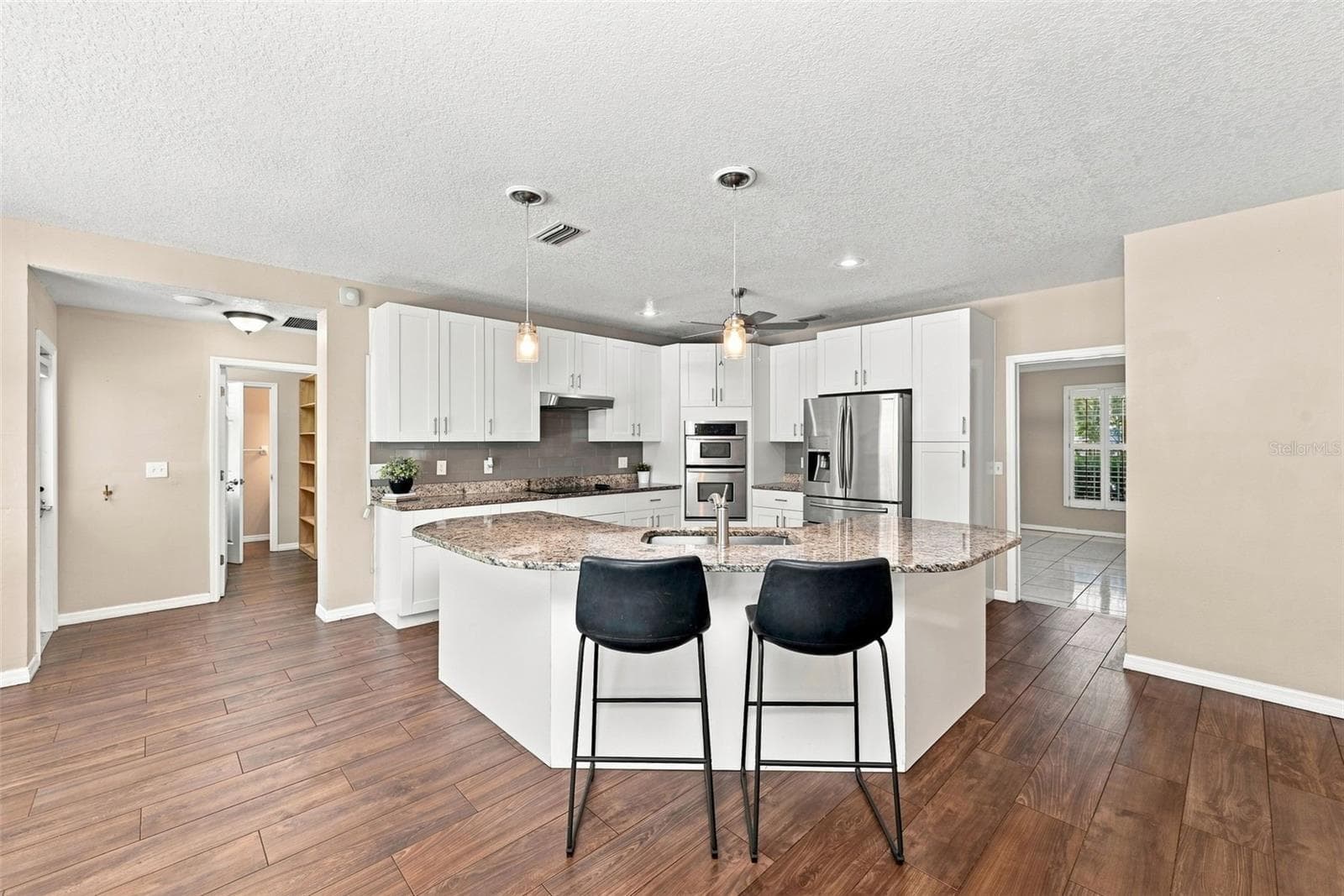 Open-Concept Kitchen with Granite Countertops offers ample cabinetry, stainless-steel appliances, generous counter space, and a large center island. - 1349 VALLEY PINE CIR, APOPKA