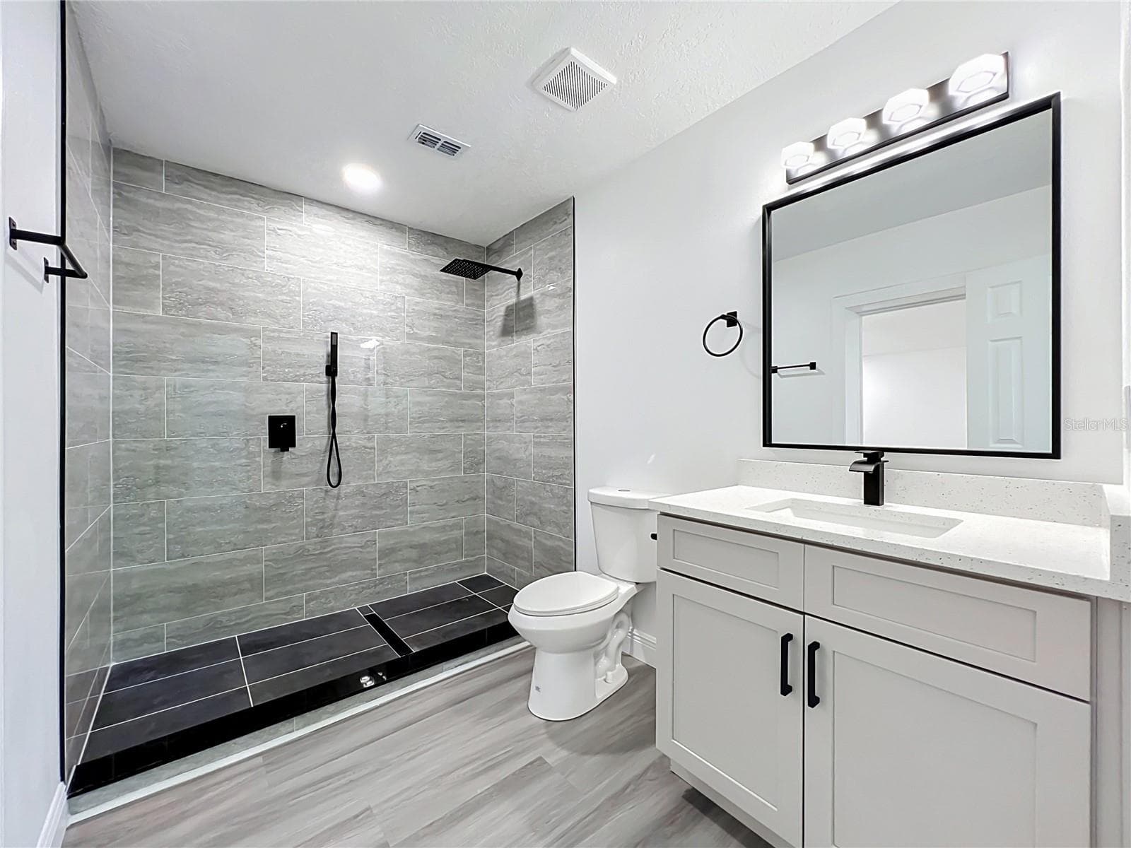 Updated bathroom featuring a modern vanity and beautifully tiled shower. - 3202 TRADEWINDS TRL, ORLANDO