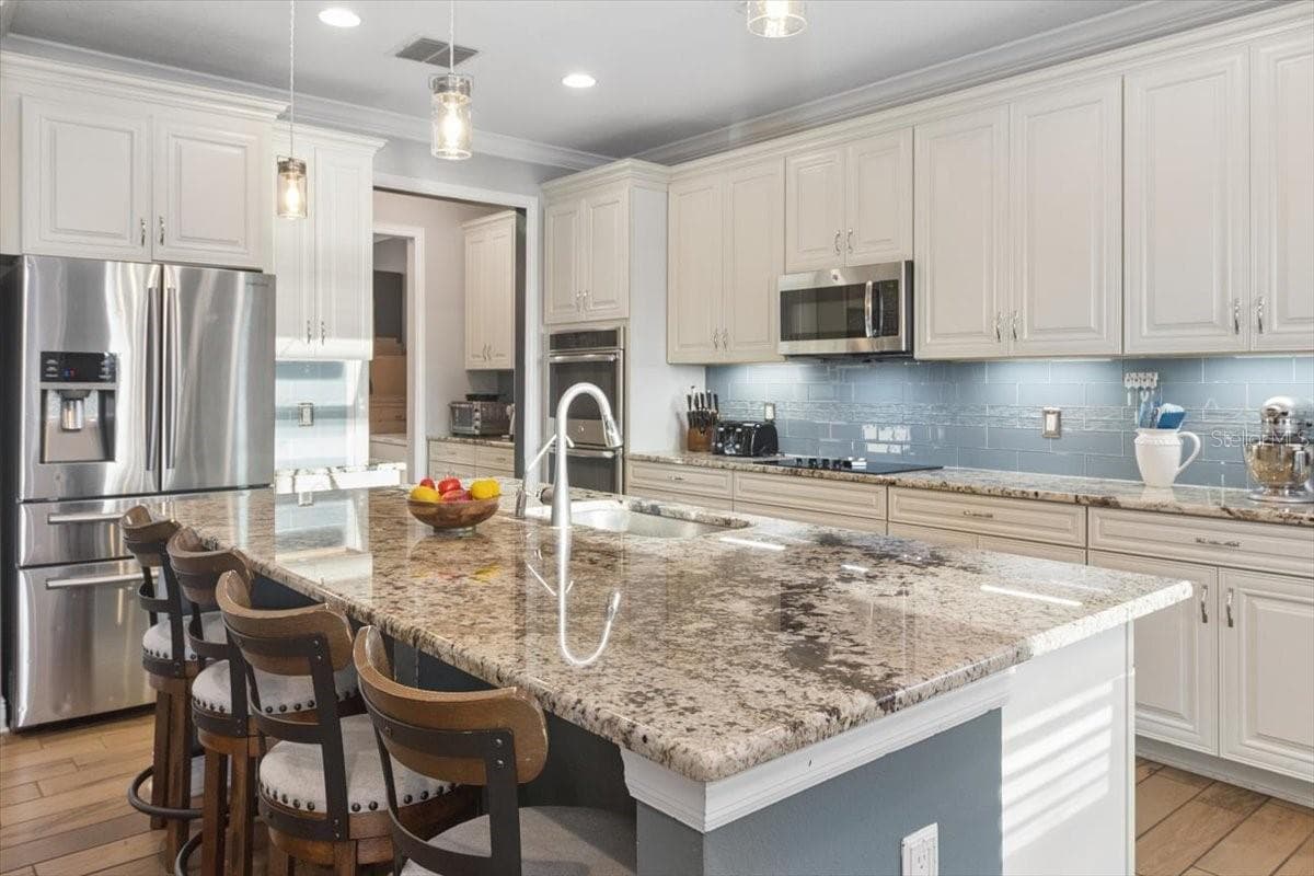 The kitchen features a spacious island with comfortable seating, creating the perfect spot for casual meals, morning coffee, or gathering with family and friends. - 19129 LONG LAKE RANCH BLVD, LUTZ