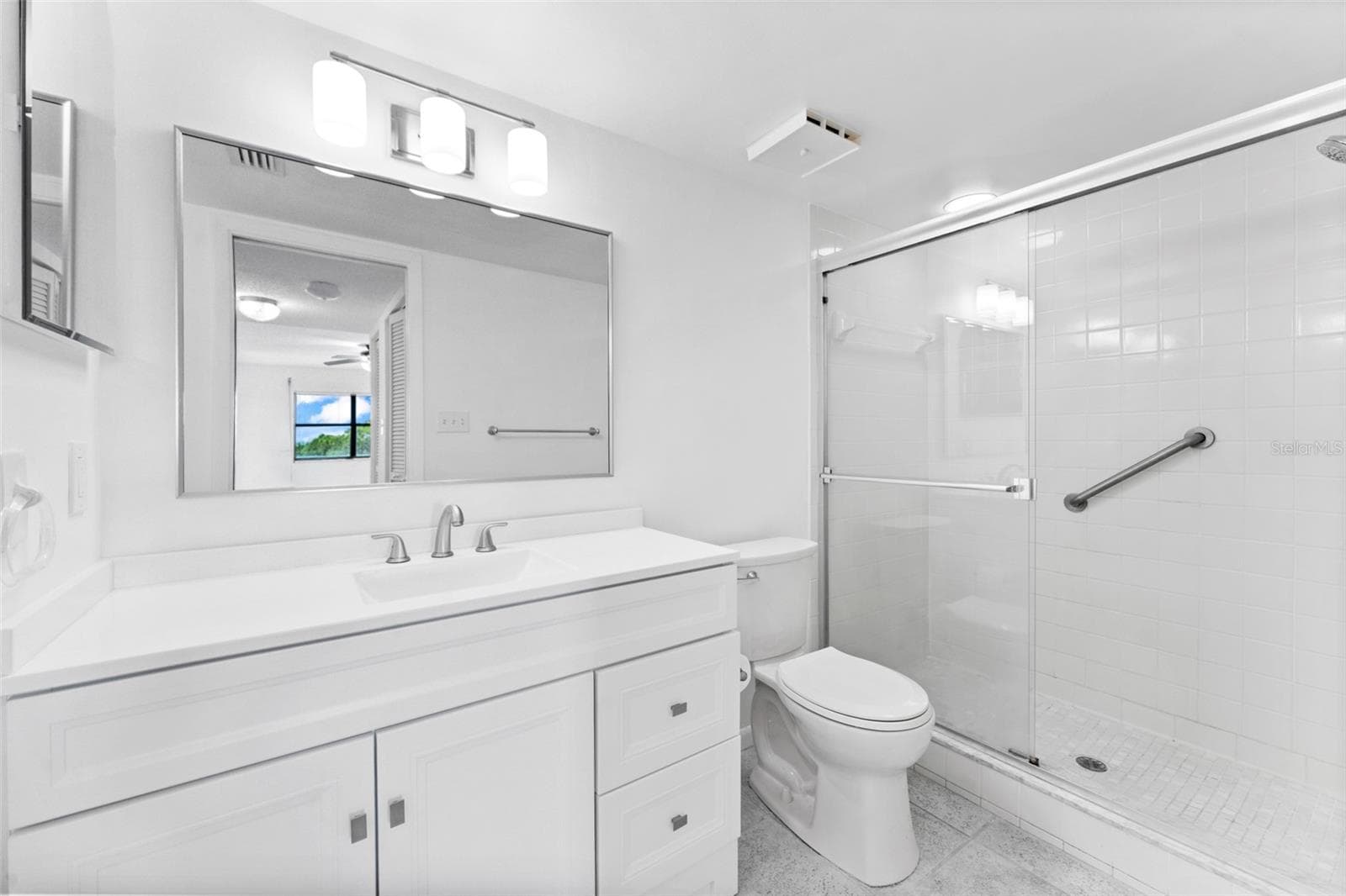 Primary bathroom with new vanity, lighting and toilet. - 5400 PARK ST N #511, ST PETERSBURG